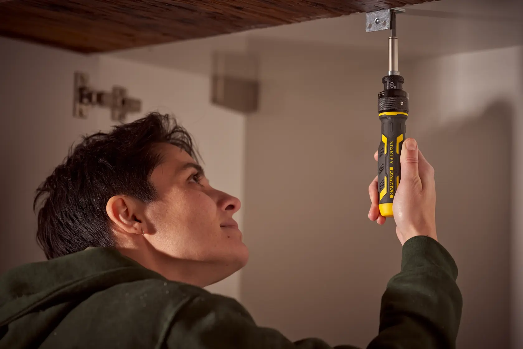 STANLEY FMHT62692-0 ratcheting screwdriver used inside cabinet, yellow and black handle visible.