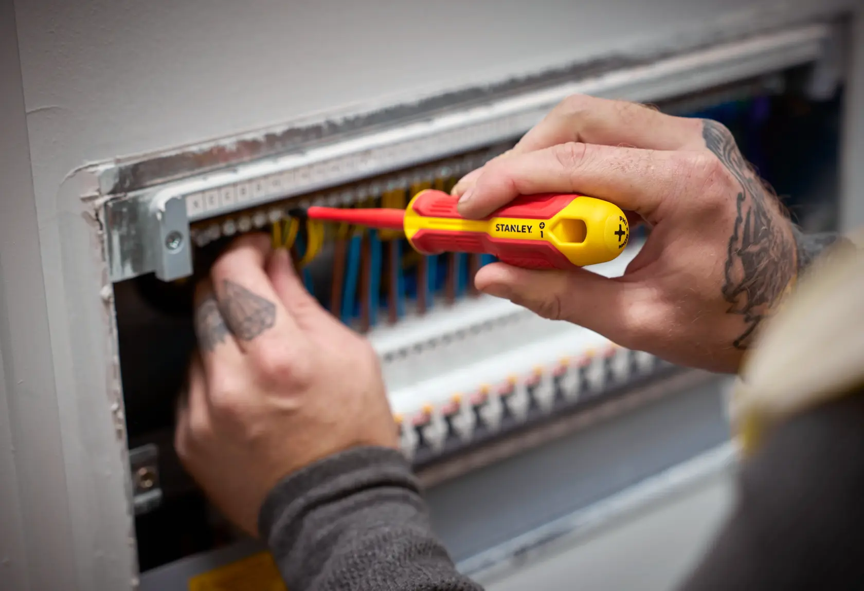 Person uses a STANLEY insulated screwdriver to work on electrical wiring in a panel.
