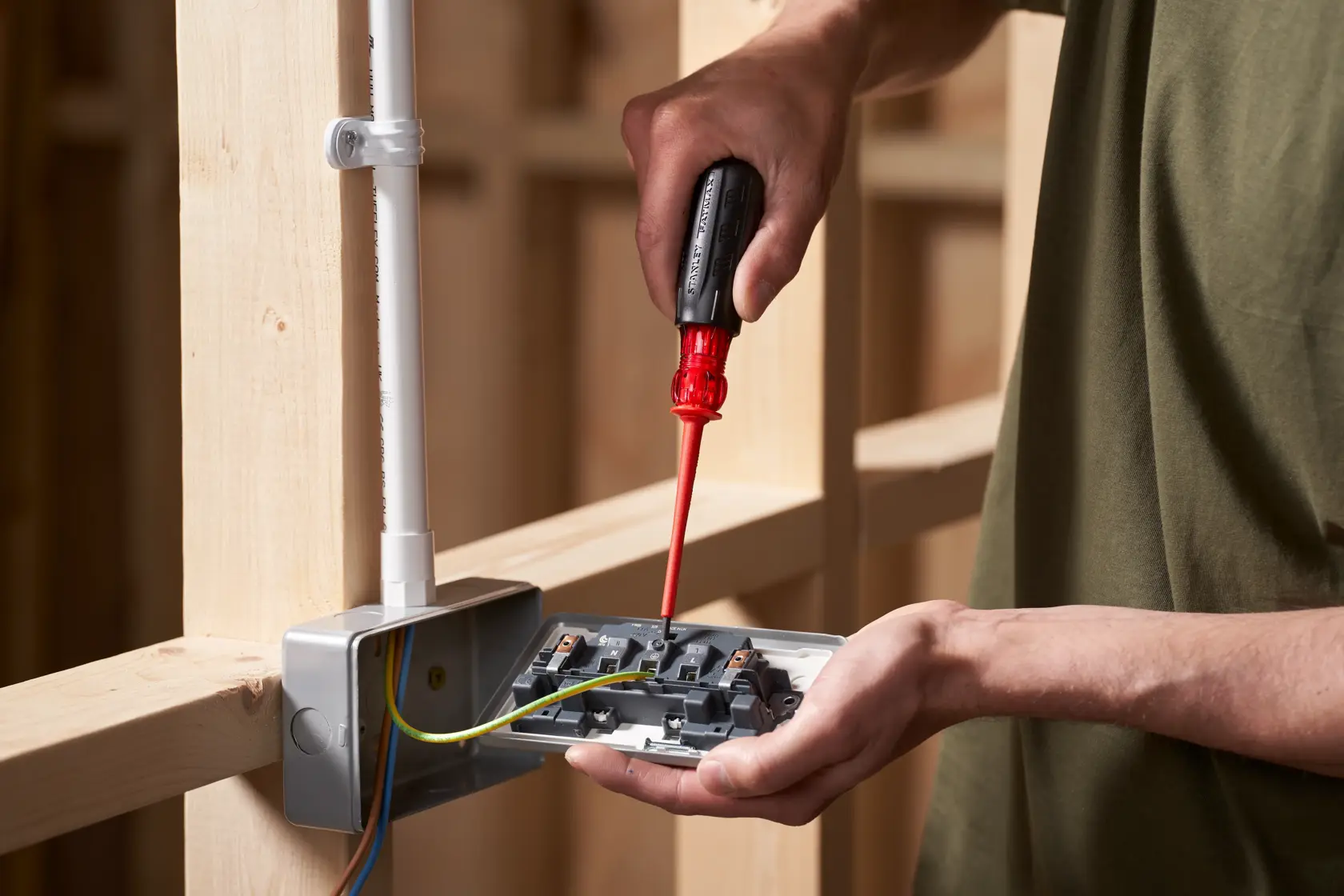 STANLEY FMHT66426-0 screwdriver used for electrical work, close-up of hand and wiring in construction setting.