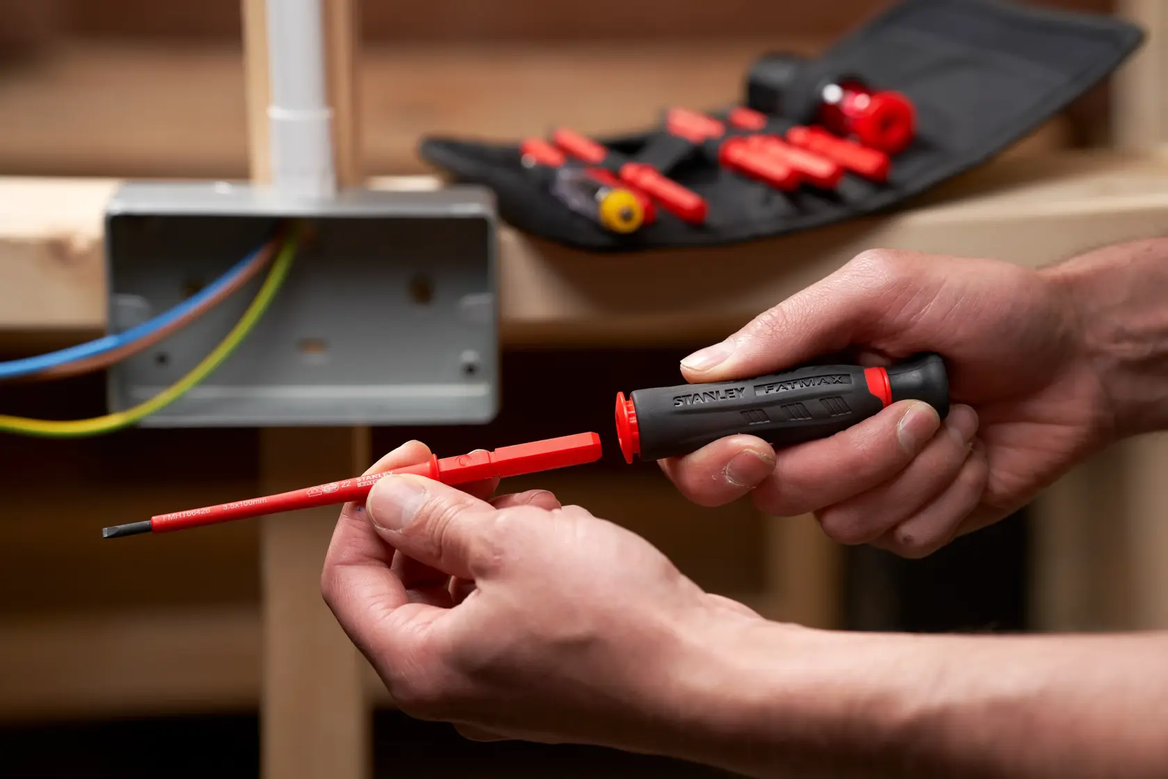 STANLEY FMHT66426-0 insulated screwdriver kit in use, featuring red interchangeable bits and pouch.