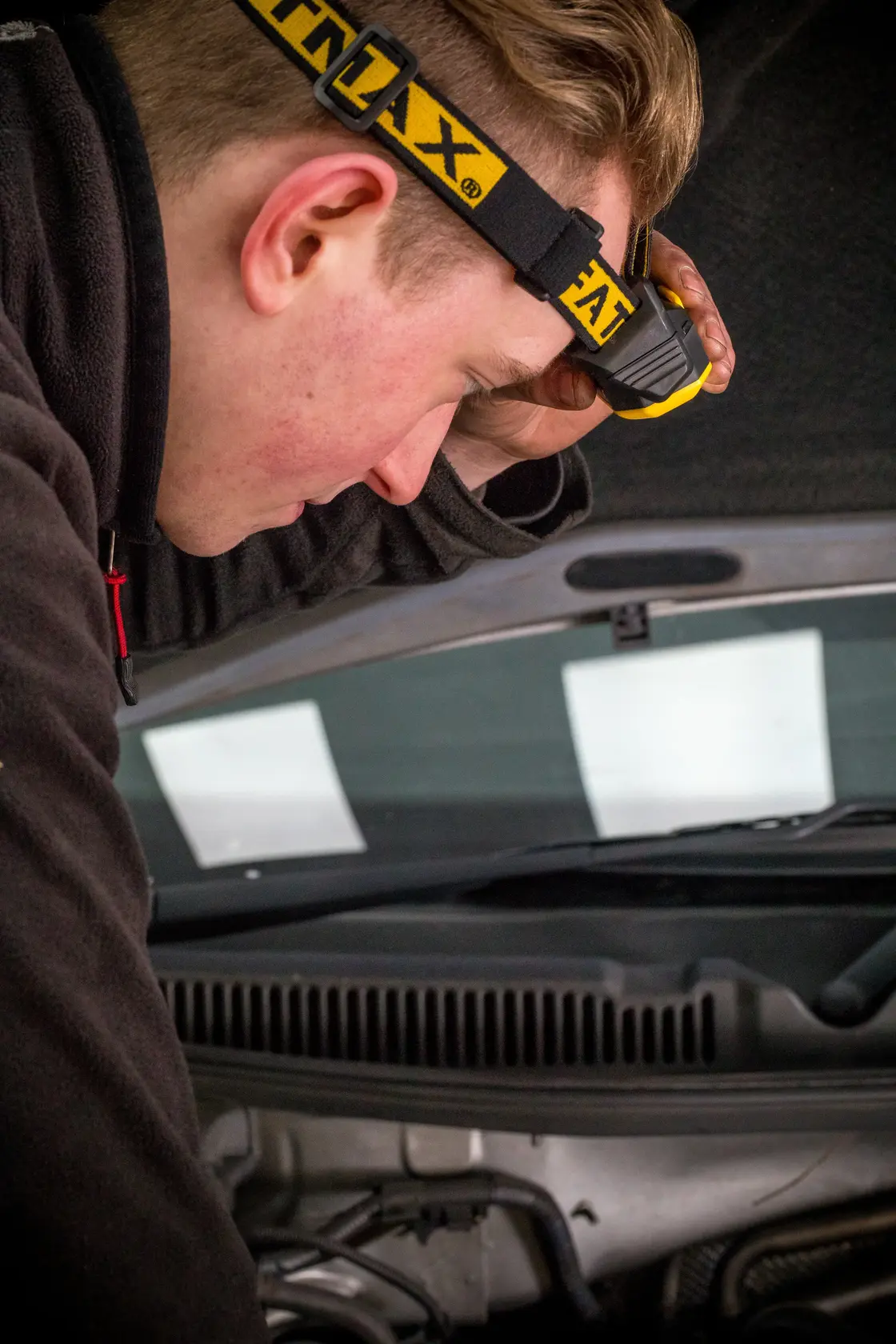Photography of STANLEY FMHT81509-0 headlamp worn by person inspecting car engine.