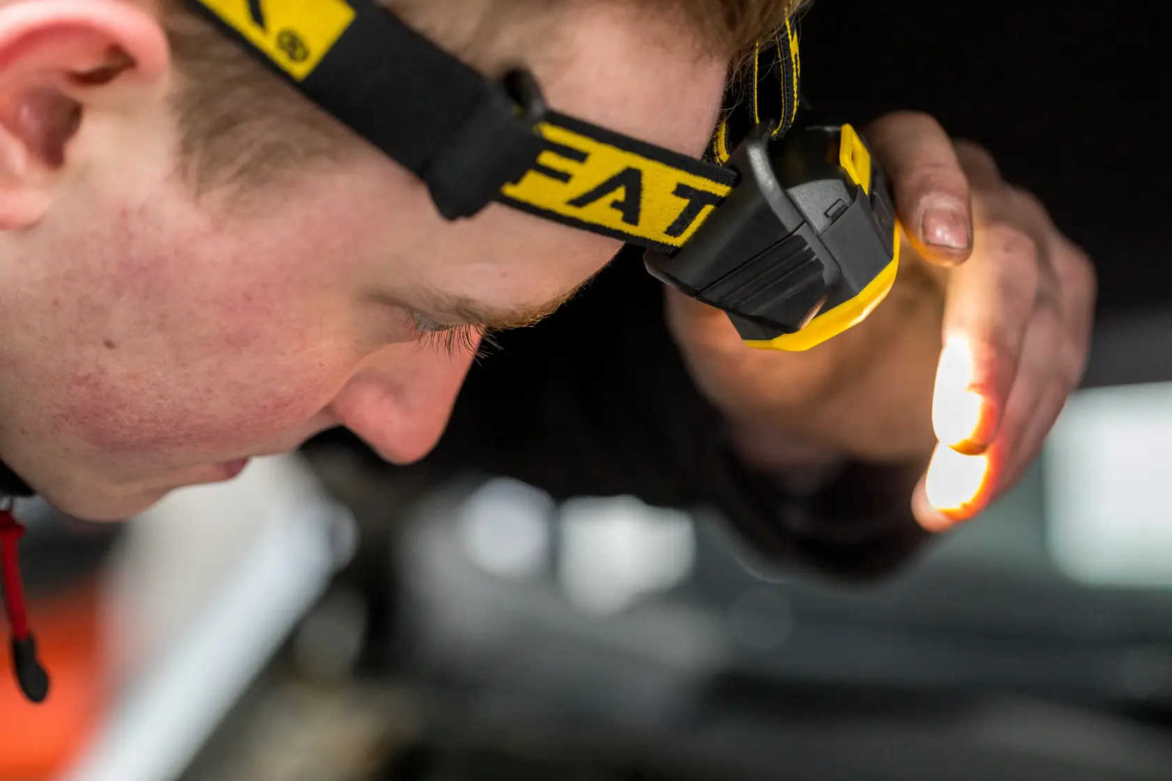 STANLEY FMHT81509-0 headlamp in use, close-up, person working hands-free with yellow and black headband.