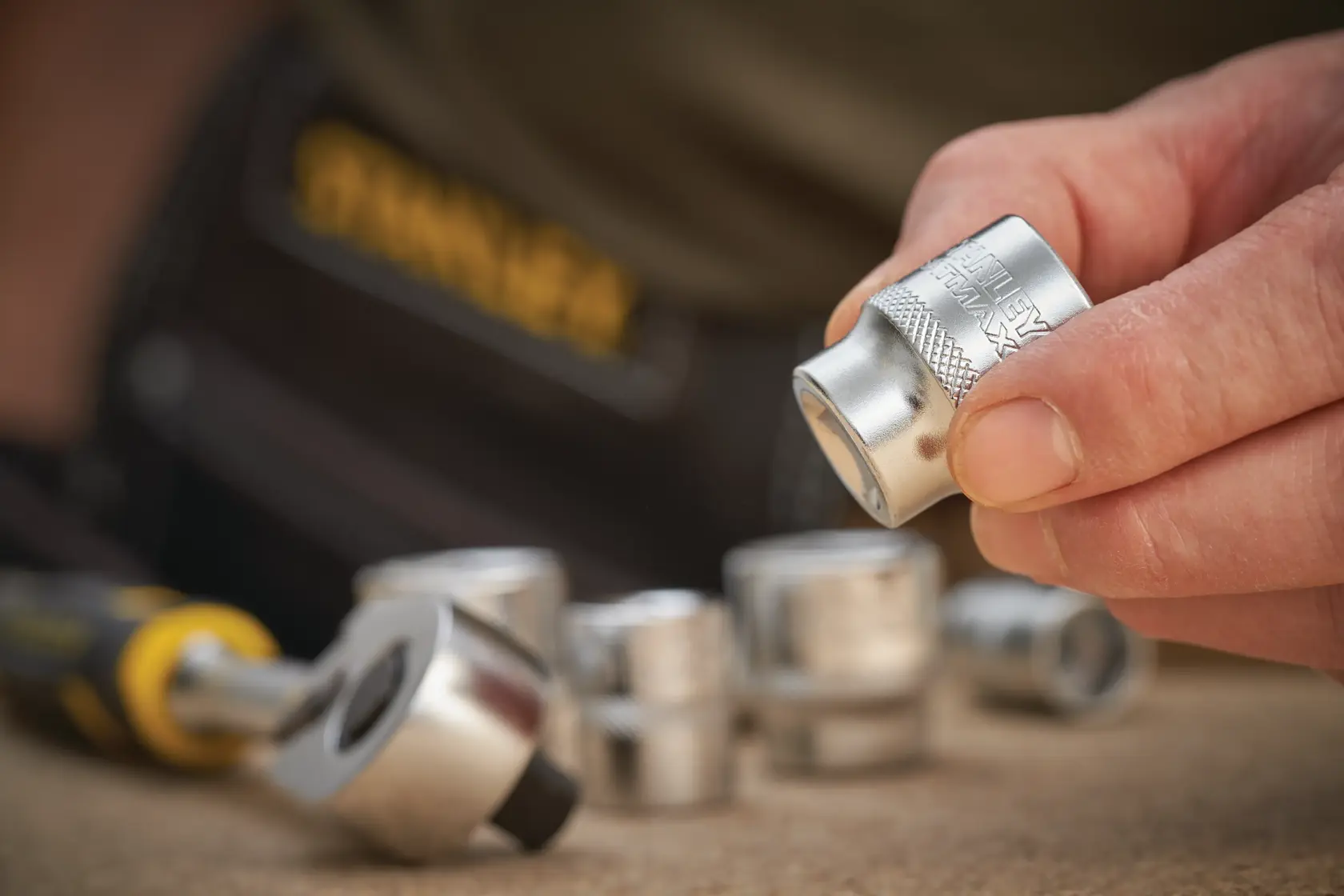 STANLEY FMMT17211-0 chrome socket held by hand with ratchet and other sockets blurred in background.