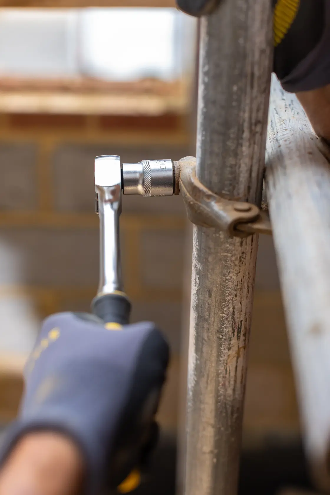 STANLEY FMMT17219-0 ratchet wrench in use, close-up, tightening a metal clamp on a scaffold.