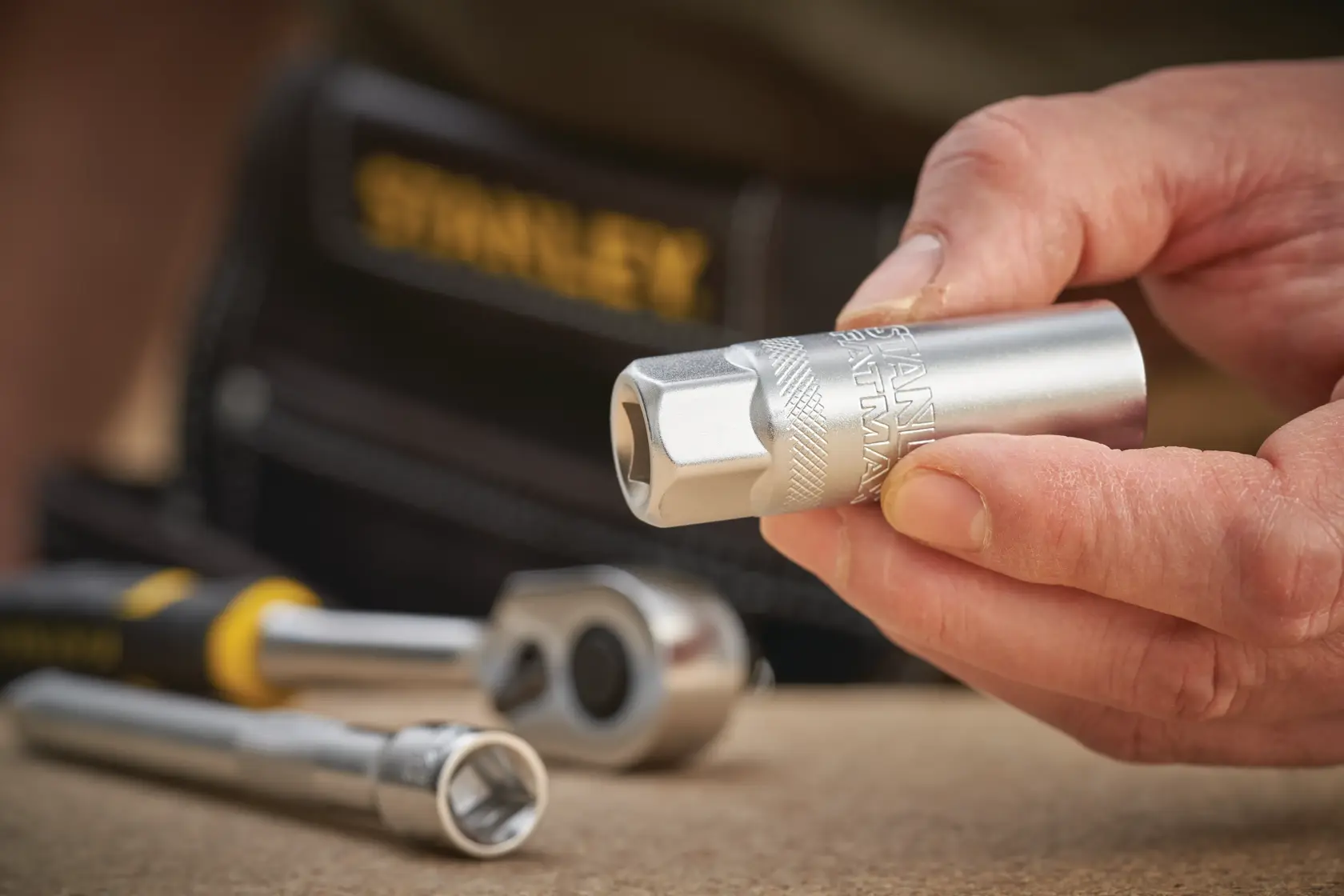STANLEY FMMT17226-0 socket held in hand, with ratchet and extension tool on work surface.