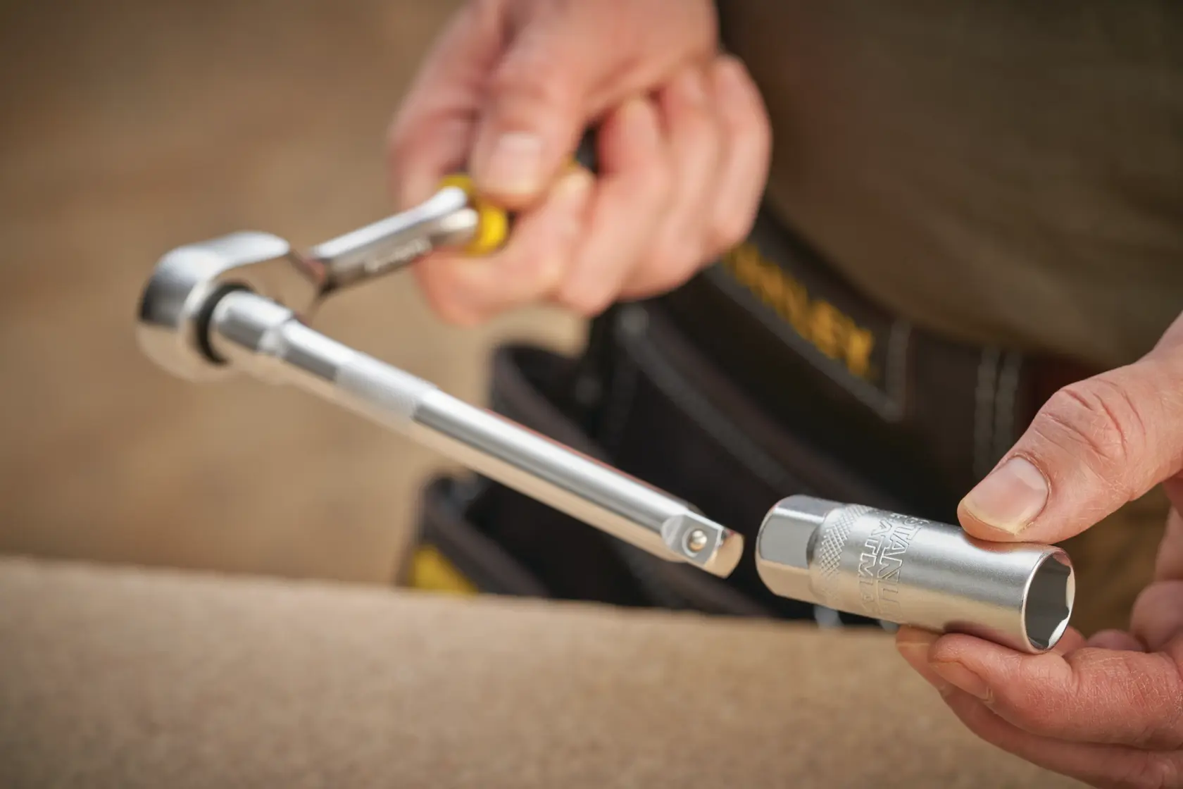 Photo of STANLEY FMMT17226-0 ratchet wrench and socket in use, held by a person wearing a tool belt.