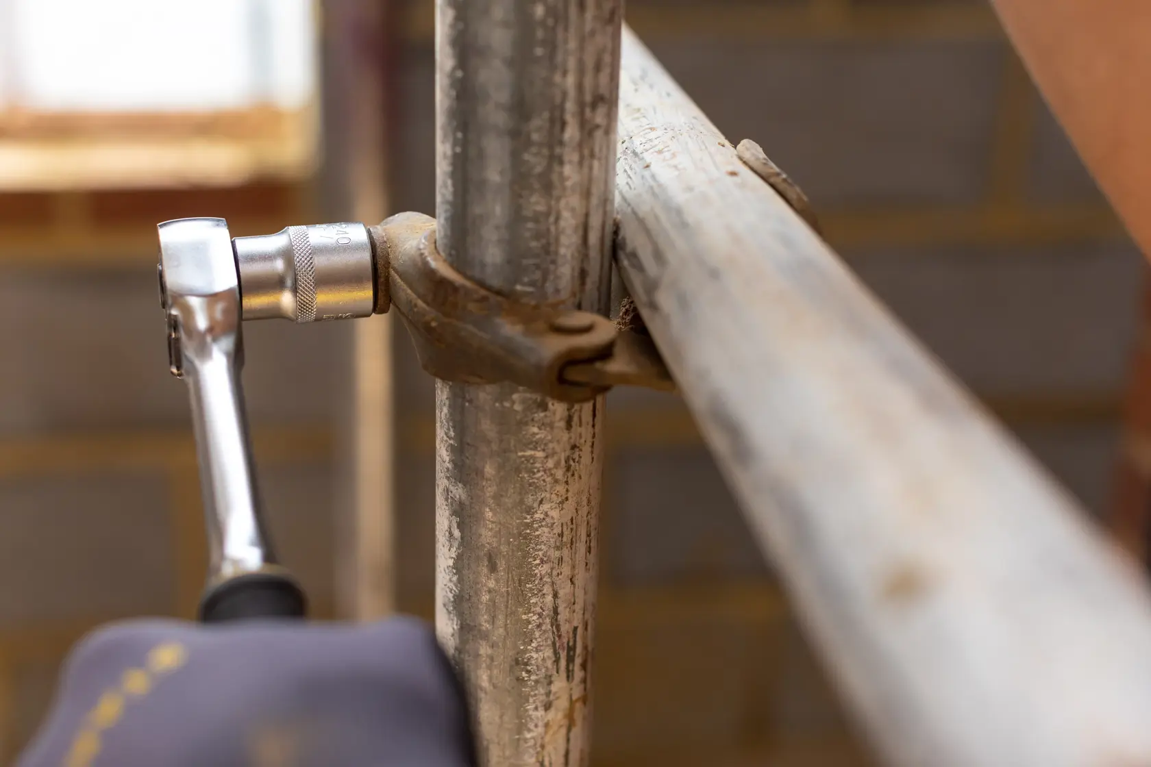 STANLEY FMMT17227-0 ratchet wrench in use tightening a metal scaffold clamp, close-up photography.