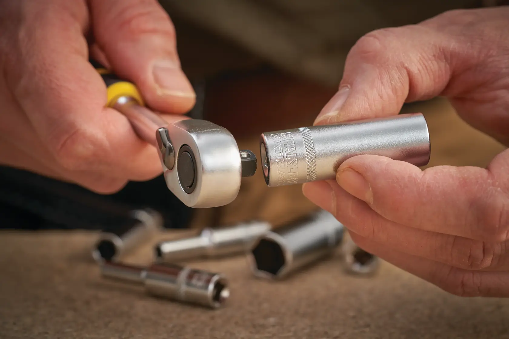 Photo of STANLEY FMMT17337-0 socket wrench and socket in hand, with sockets on work surface, close-up.