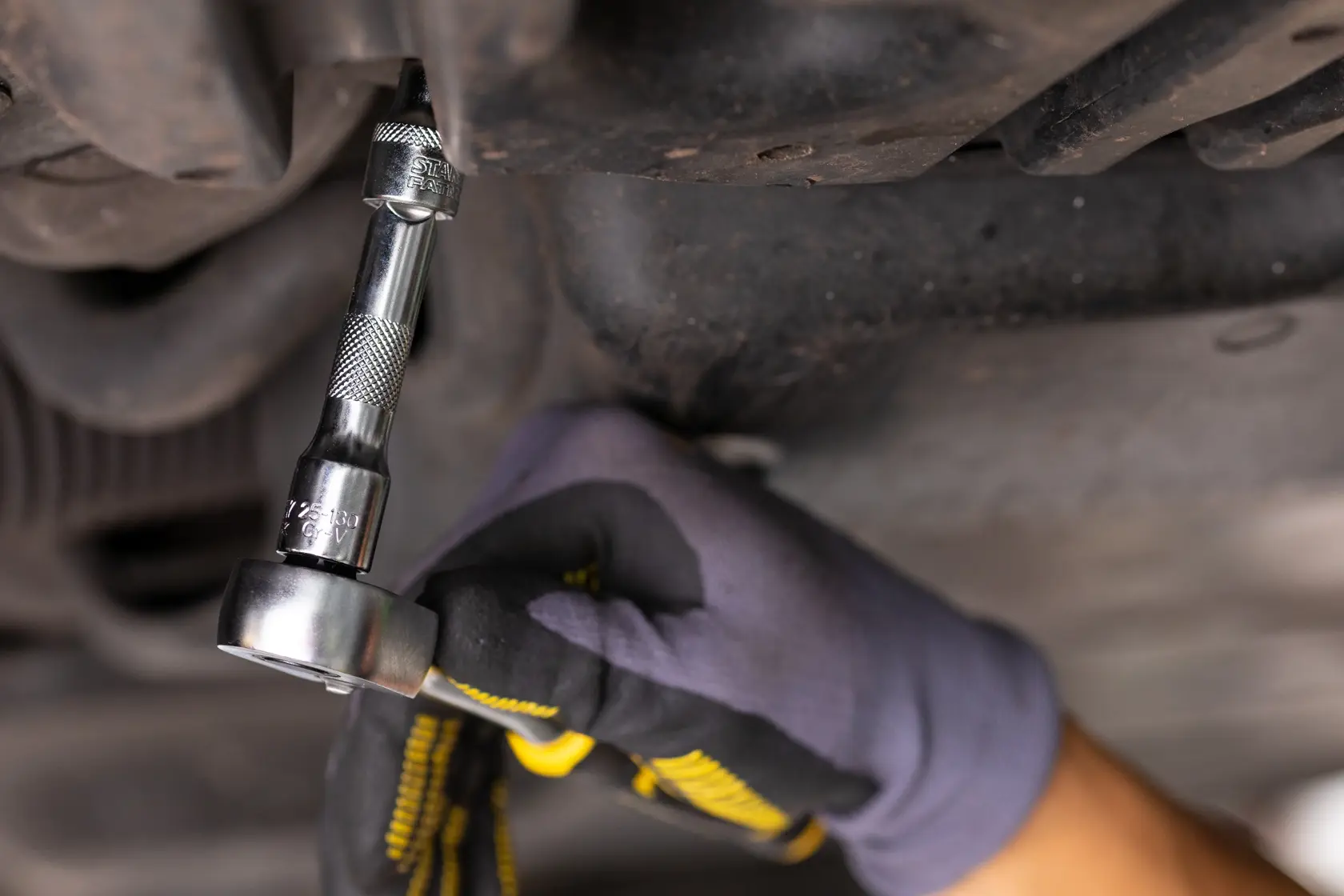STANLEY FMMT25125-0 socket wrench in use on a bolt, close-up, automotive repair, gloved hand.