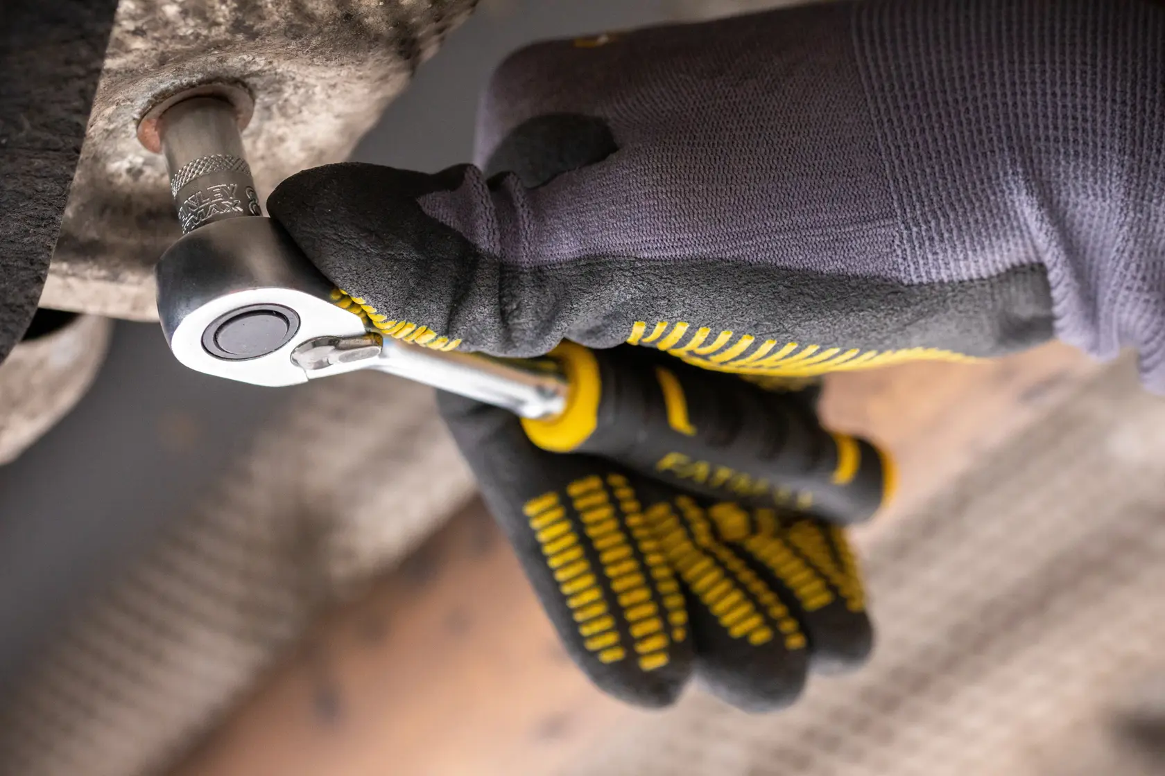 STANLEY FMMT82676-0 ratchet wrench in use, photographed close-up with gloved hand tightening a bolt.