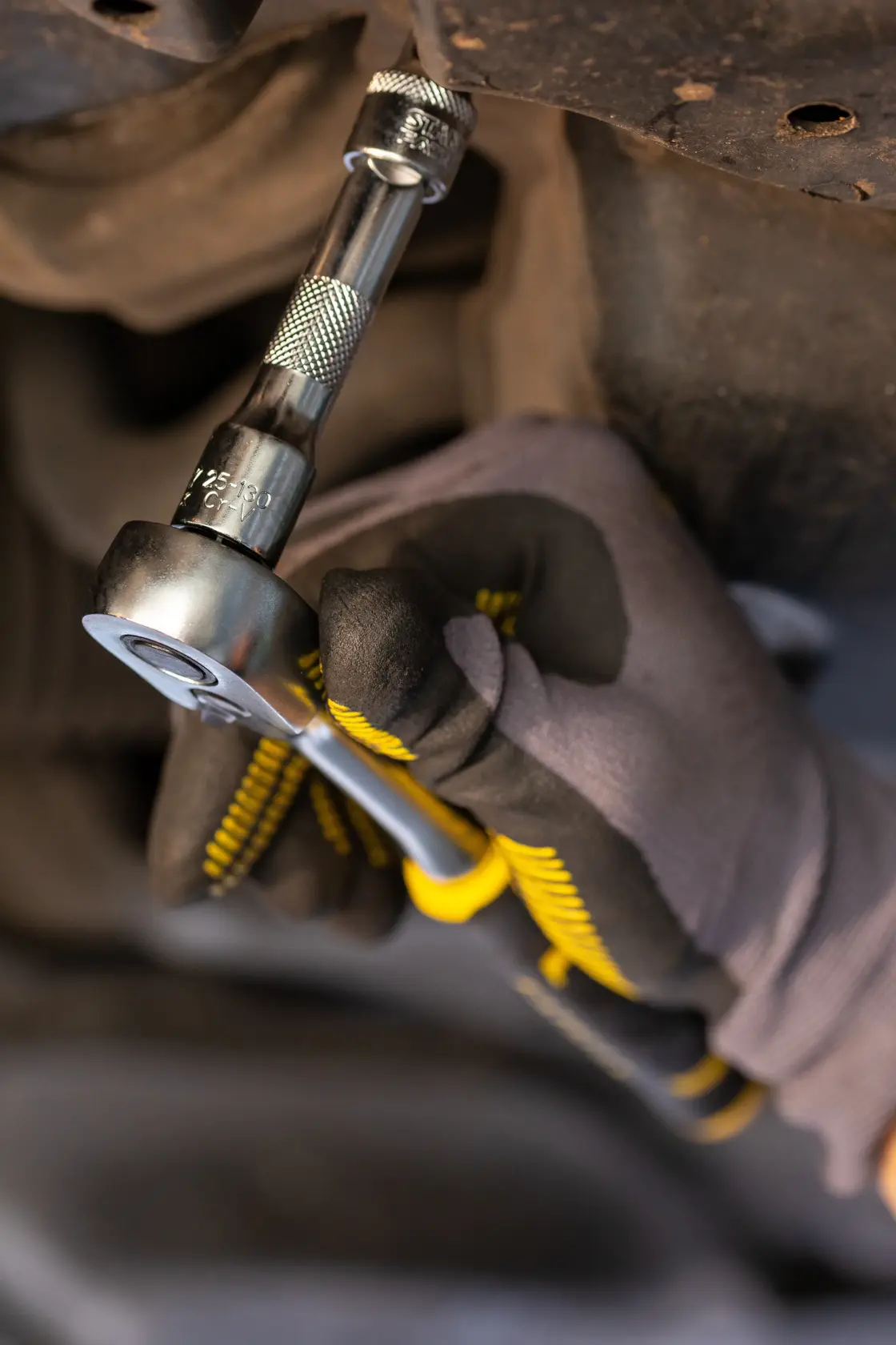STANLEY FMMT82677-0 ratchet wrench in use, held by gloved hand tightening a bolt, close-up view.
