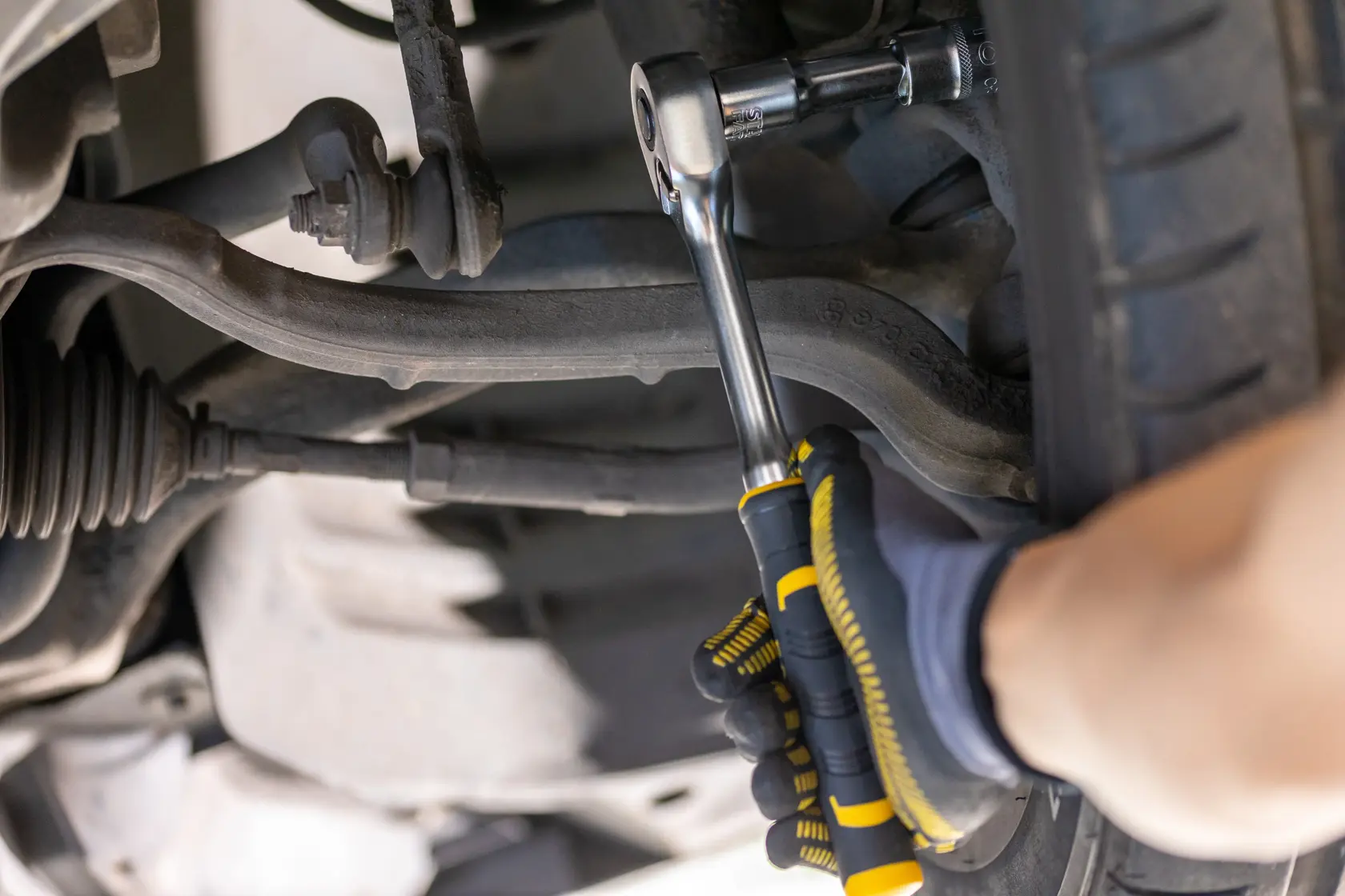 STANLEY FMMT82677-0 ratchet wrench in use tightening a bolt on a car suspension, close-up photography.