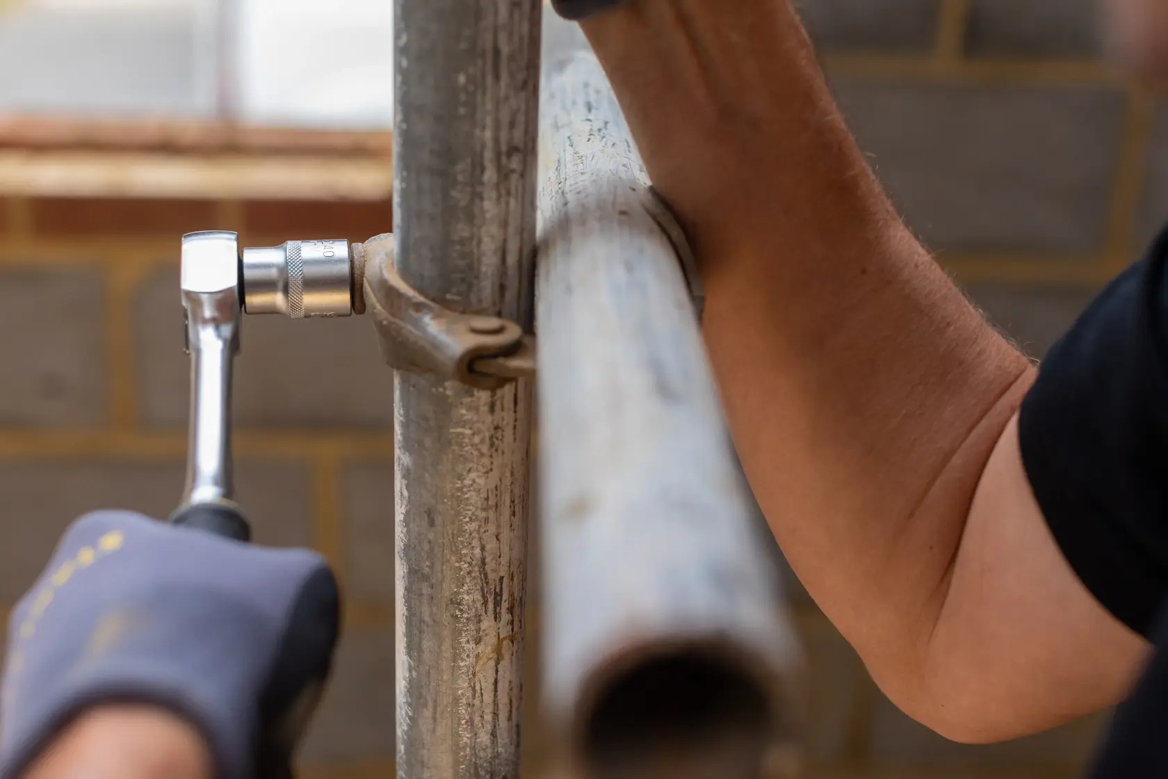 STANLEY FMMT82678-0 ratchet tool used to tighten scaffolding clamp in close-up construction scene.