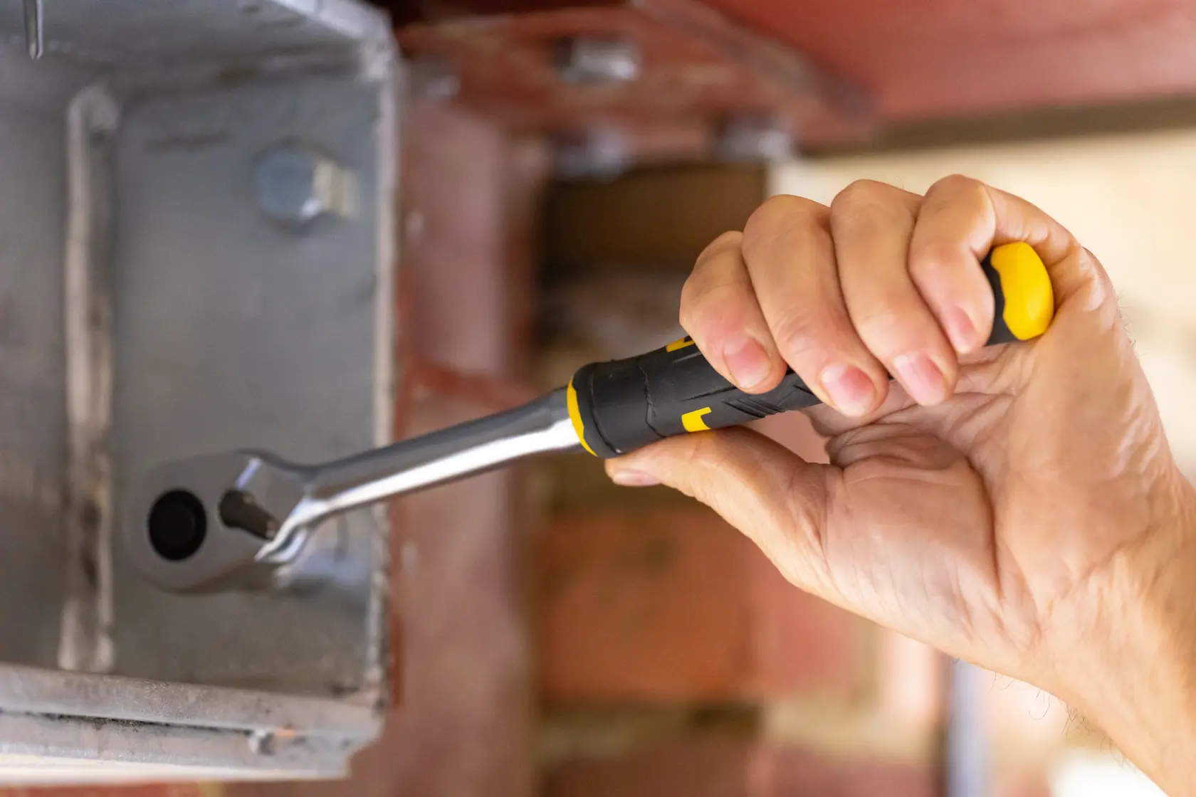 STANLEY FMMT82678-0 ratchet wrench with black and yellow handle used on metal fixture, close-up photography.