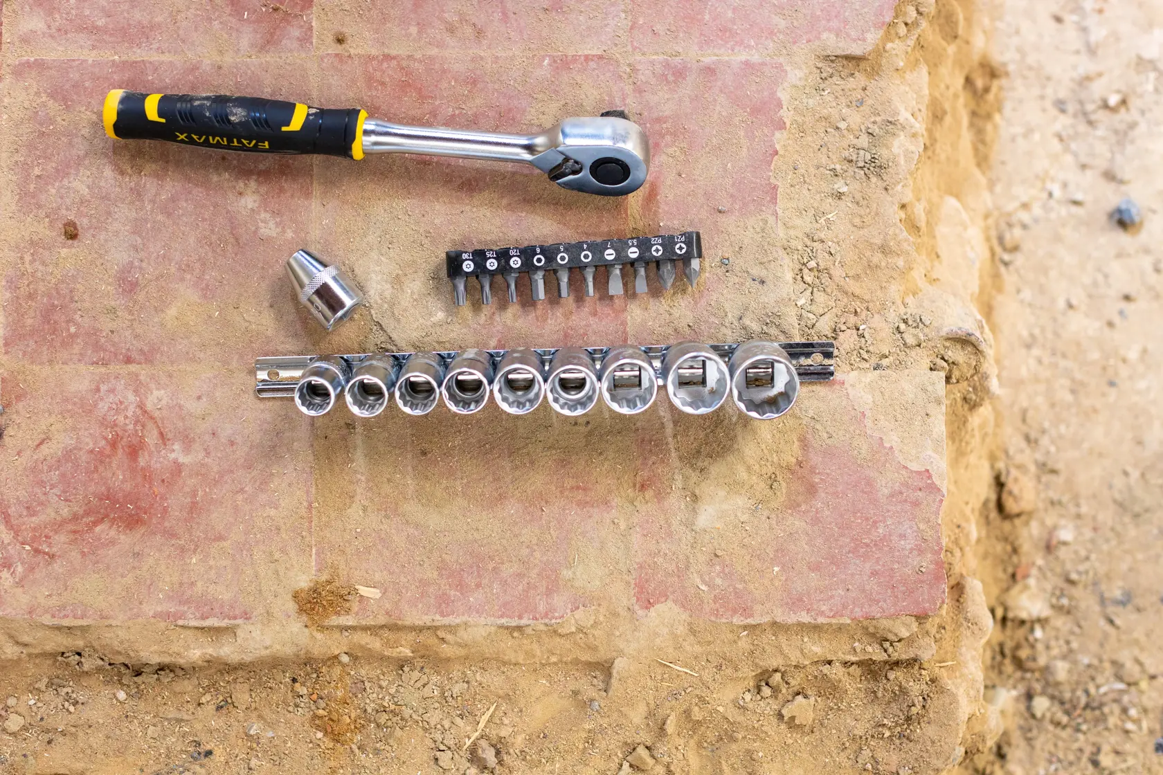 STANLEY FMMT82679-0 ratchet wrench and socket set with bits, top view on outdoor stone surface.