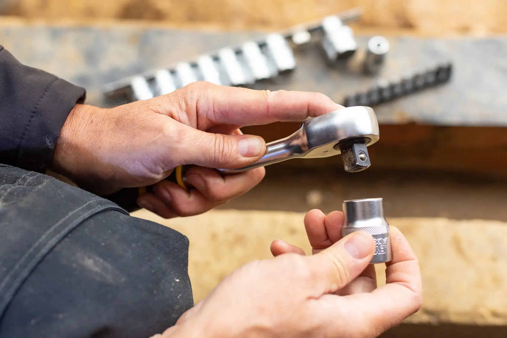 Photo of STANLEY FMMT82679-0 ratchet wrench and socket held in hands, with sockets set in background.