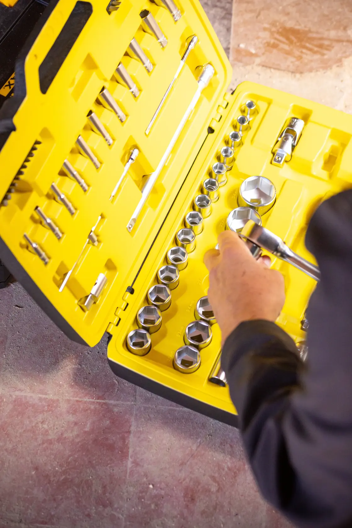 STANLEY FMMT82684-1 socket set photography, yellow case open, hand holding socket, top-down angle.