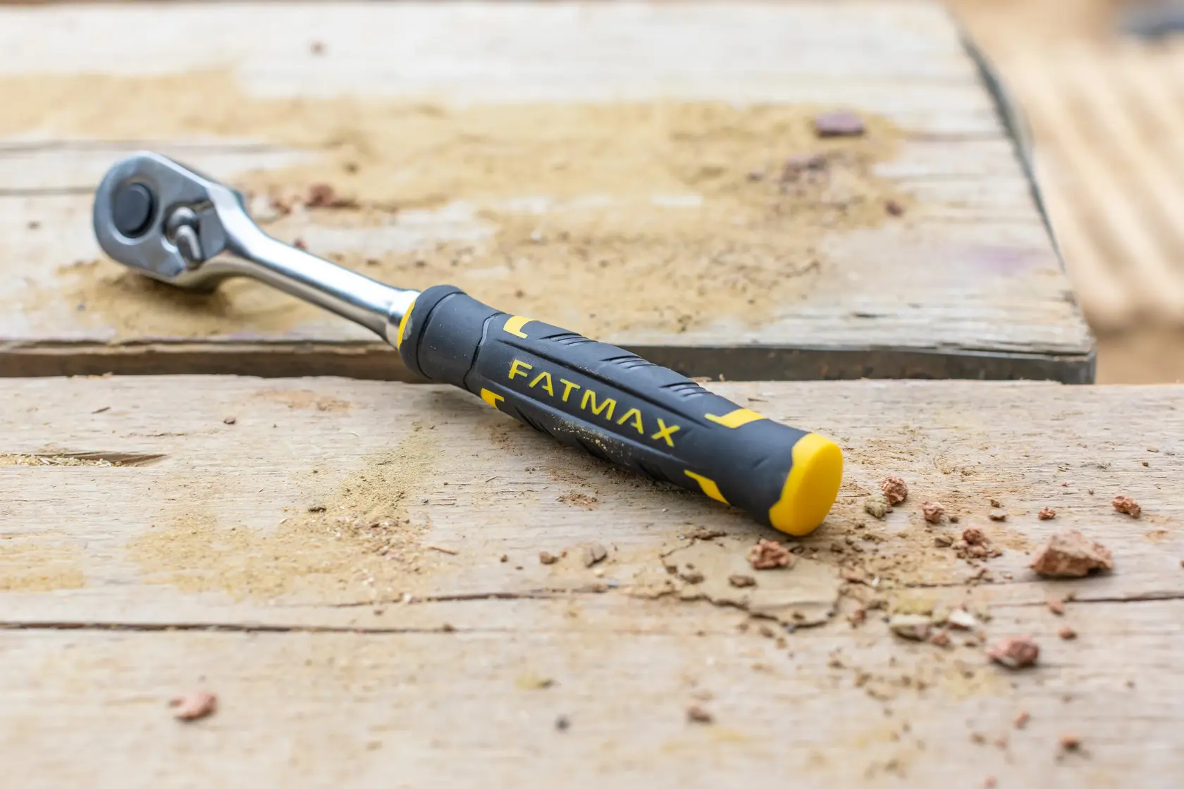 STANLEY FMMT82684-1 ratchet wrench with black and yellow FATMAX handle on a sandy wooden surface.