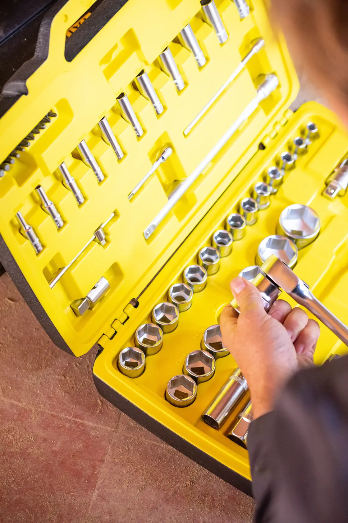 STANLEY FMMT82826-1 socket set with yellow case, showing hand selecting a socket, top view.