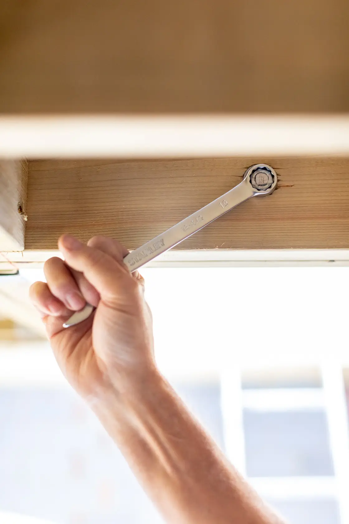 STANLEY FMMT82845-0 wrench in use tightening a bolt on wooden frame, close-up photography.