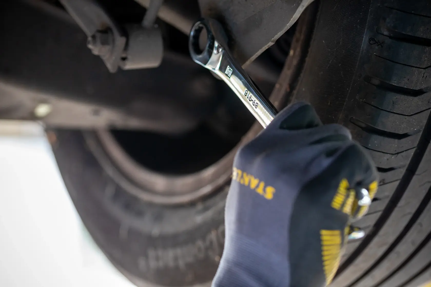 STANLEY FMMT82848-0 ratcheting wrench photography used on car wheel by gloved hand.