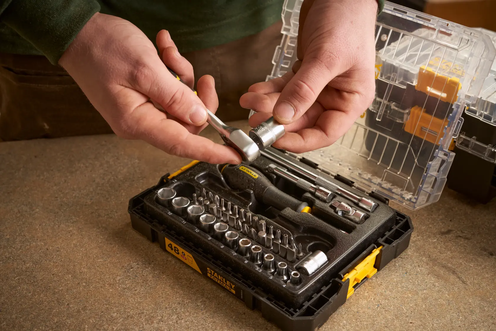STANLEY FMMT98101-0 socket and ratchet set photographed in use, with black case open on workbench.