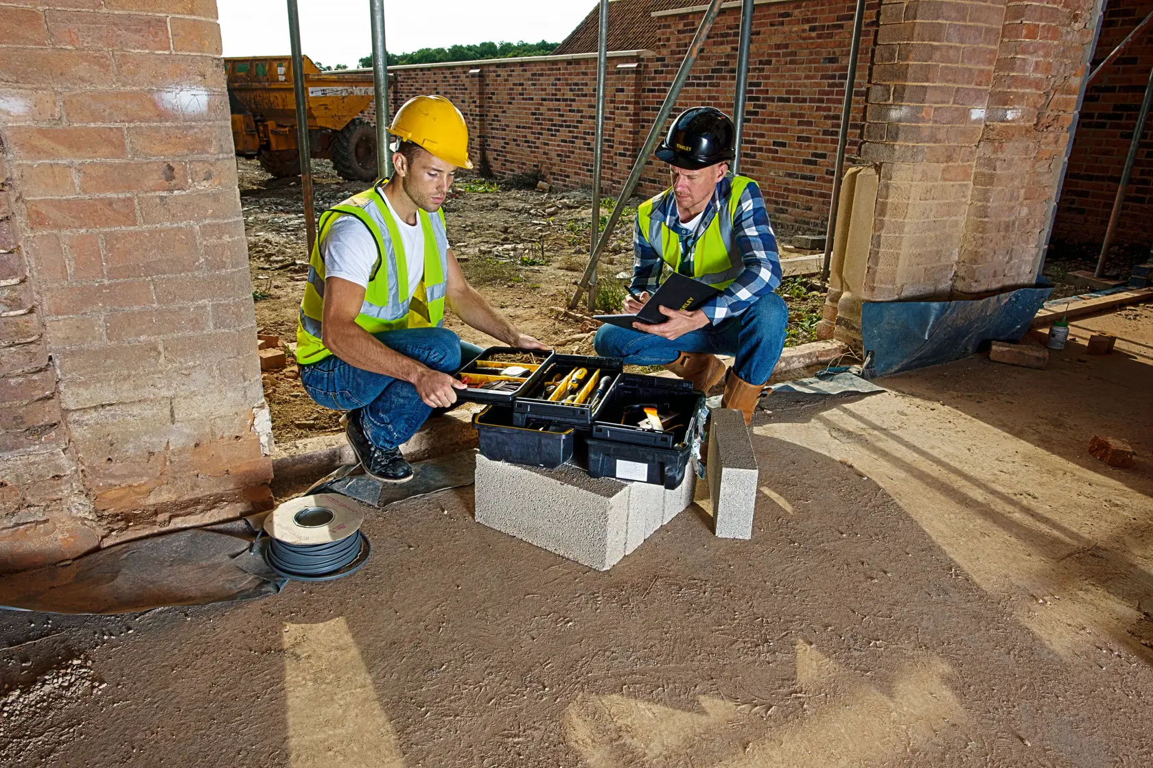 STANLEY FMST1-71219 tool box open on site, showing hand tools, used by two construction workers.