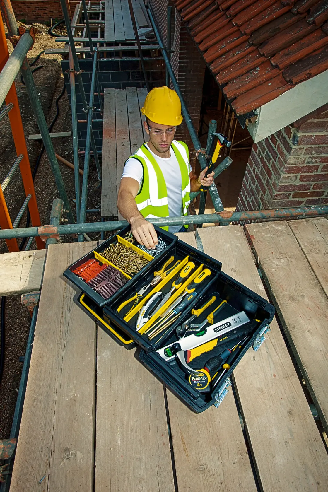 STANLEY FMST1-71219 toolbox open on construction site with assorted hand tools and fasteners.