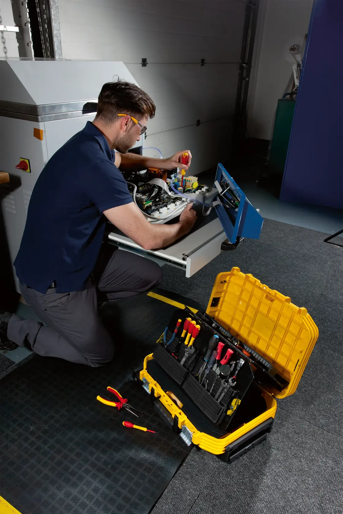Photo of STANLEY FMST1-71943 tool box open with tools, beside a worker in workshop setting.