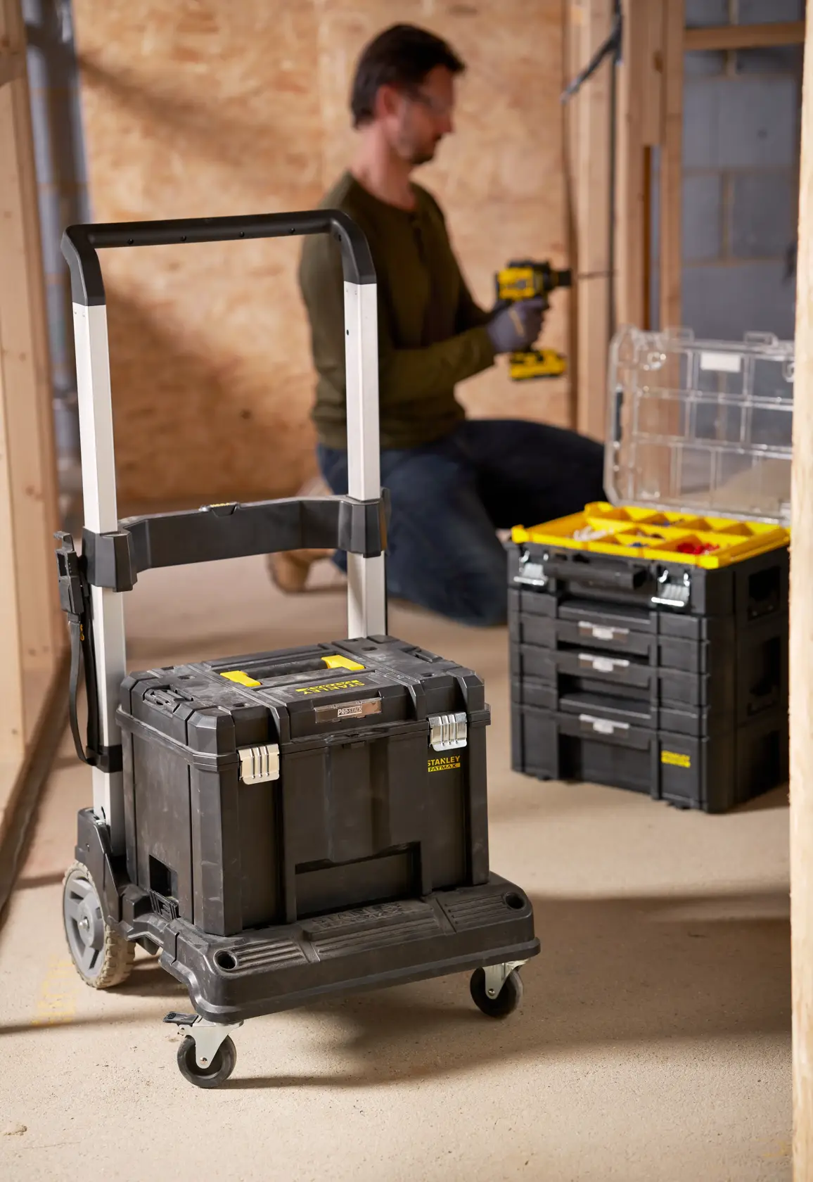 STANLEY FMST1-72363 black rolling tool box with telescopic handle in workshop setting.