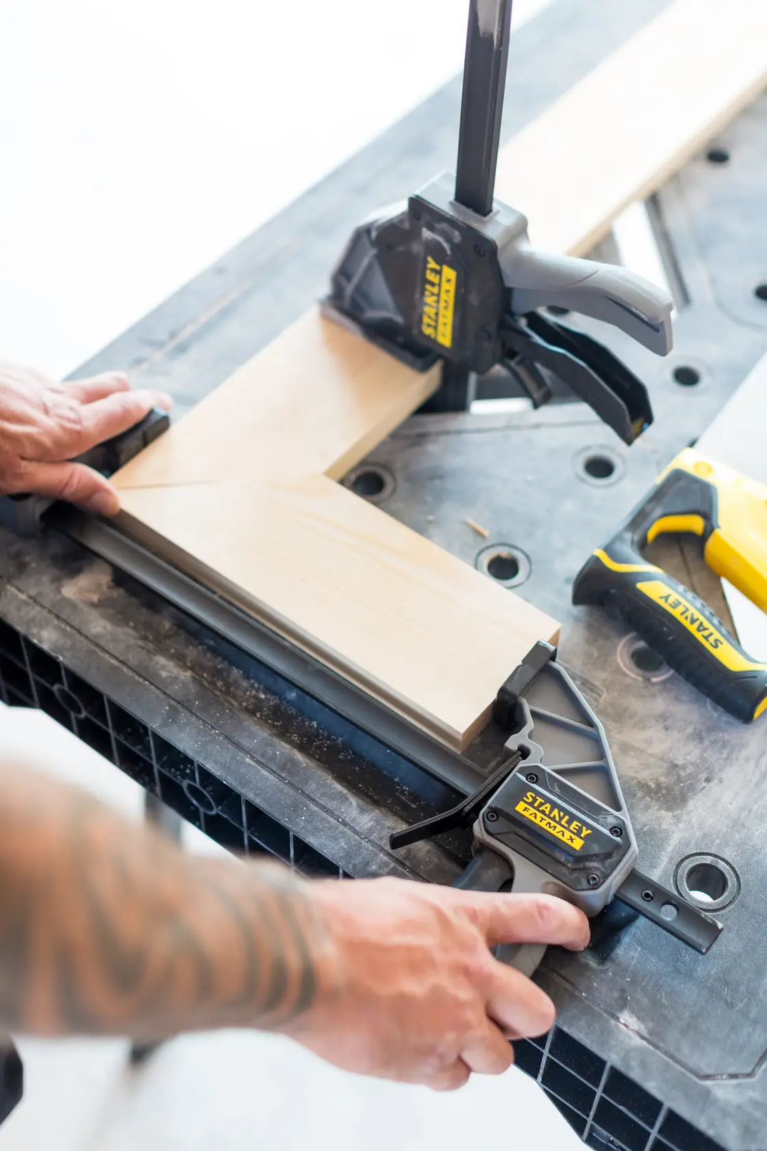 STANLEY FMST1-75672 woodworking clamp securing two wooden boards at a right angle on a workbench, close-up.