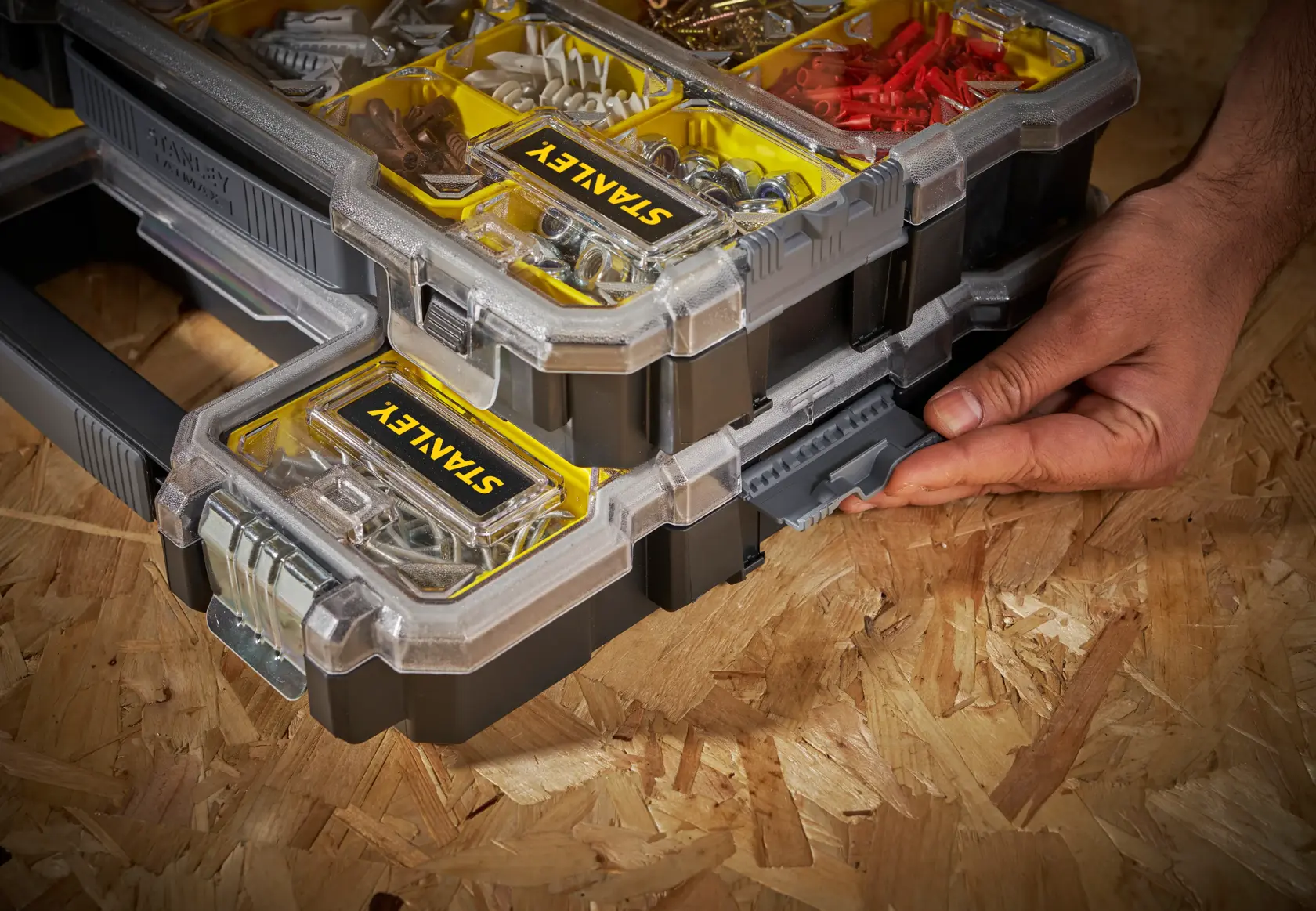 STANLEY FMST1-75779 stackable organizer with yellow compartments, hand operating side latch, angled view.