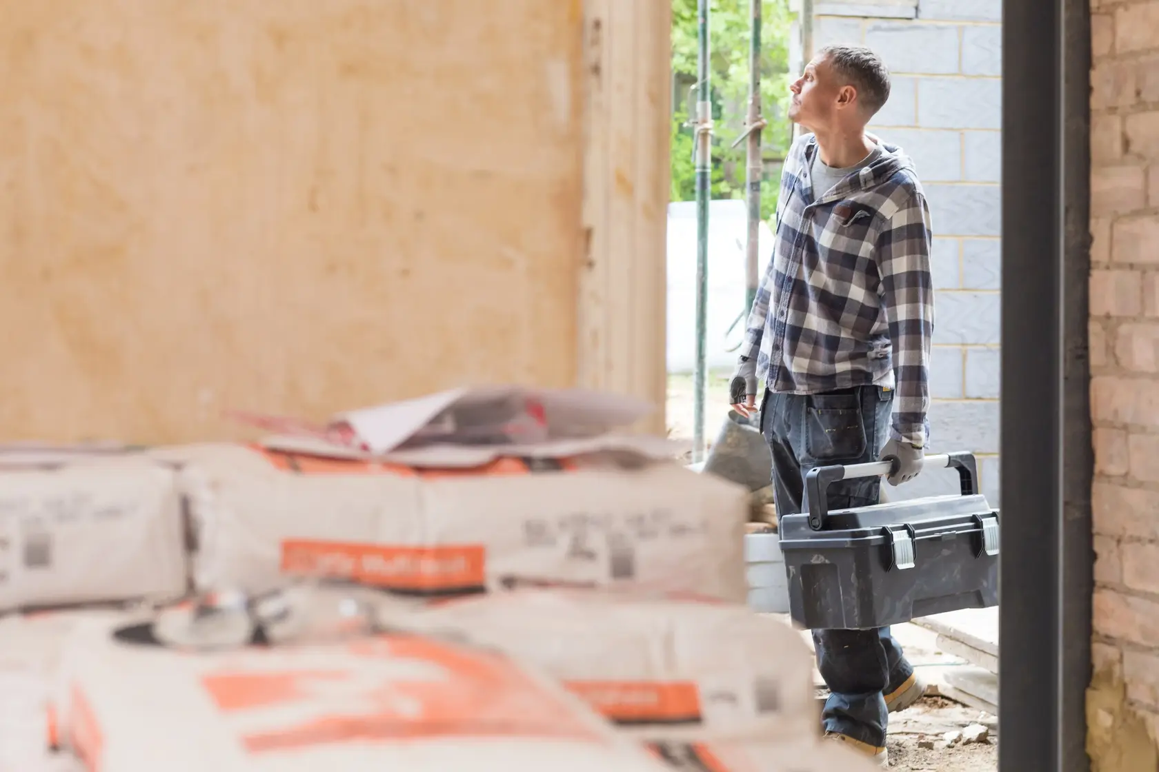 STANLEY FMST1-75791 toolbox carried by worker in plaid shirt at construction site, partial view.