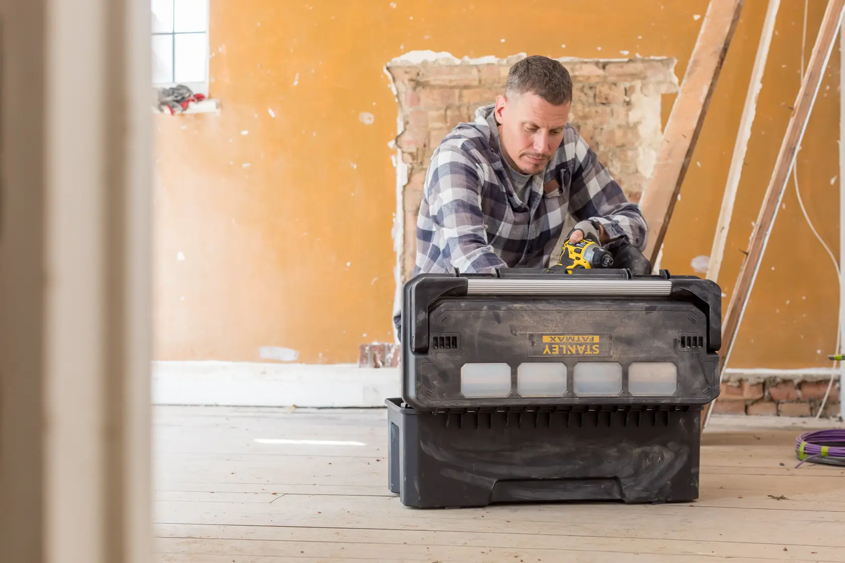Stanley FMST1-75791 toolbox in use at construction site, black plastic with clear compartments, front angle.