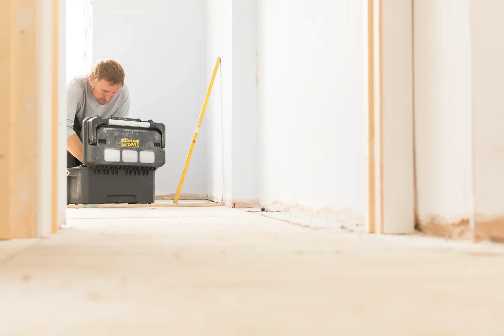 STANLEY FMST1-75792 tool box in use in a hallway, black case with yellow branding, person in background.
