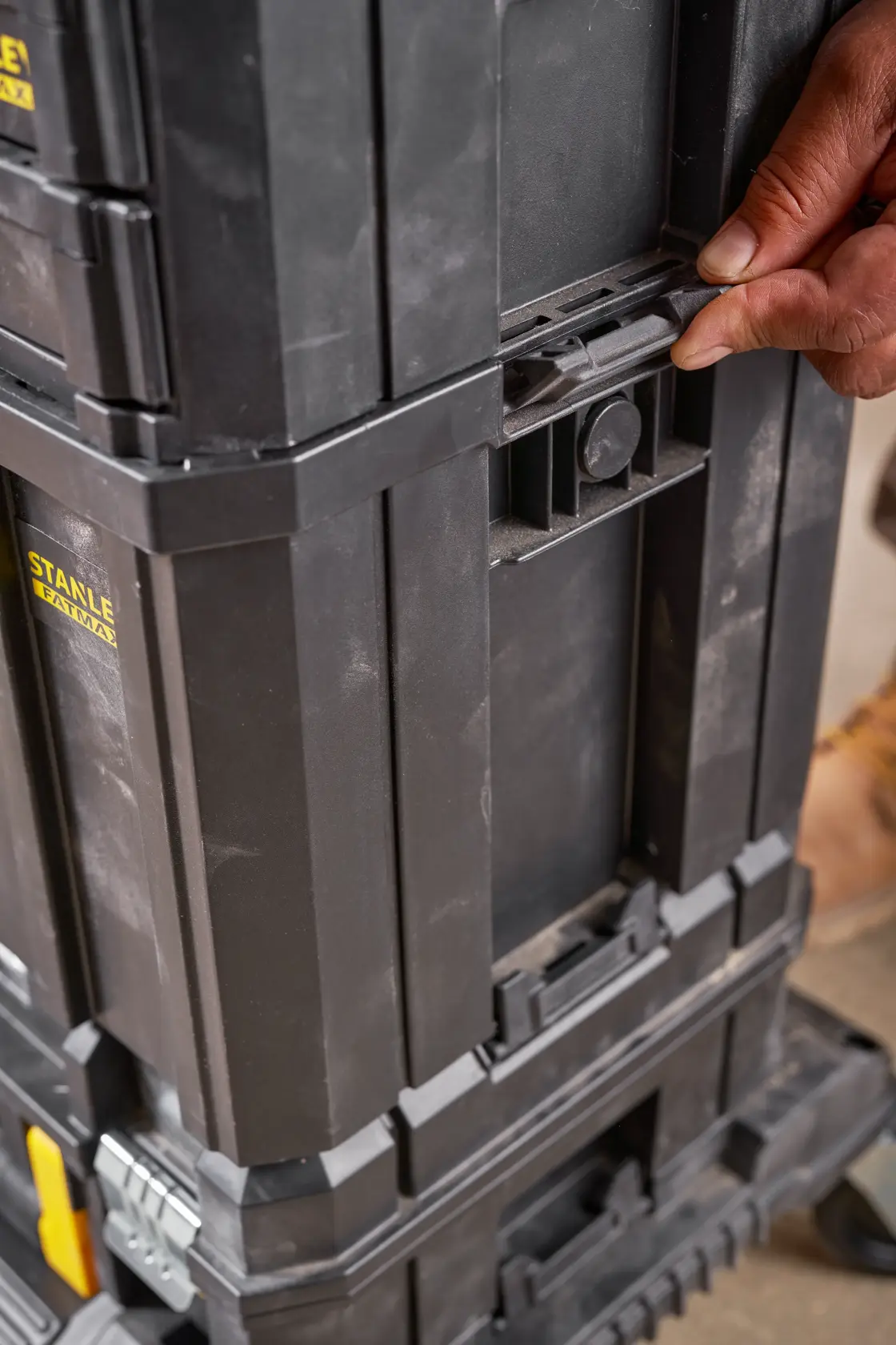 STANLEY FMST1-75794 black stackable tool box, side view, hand using locking latch.