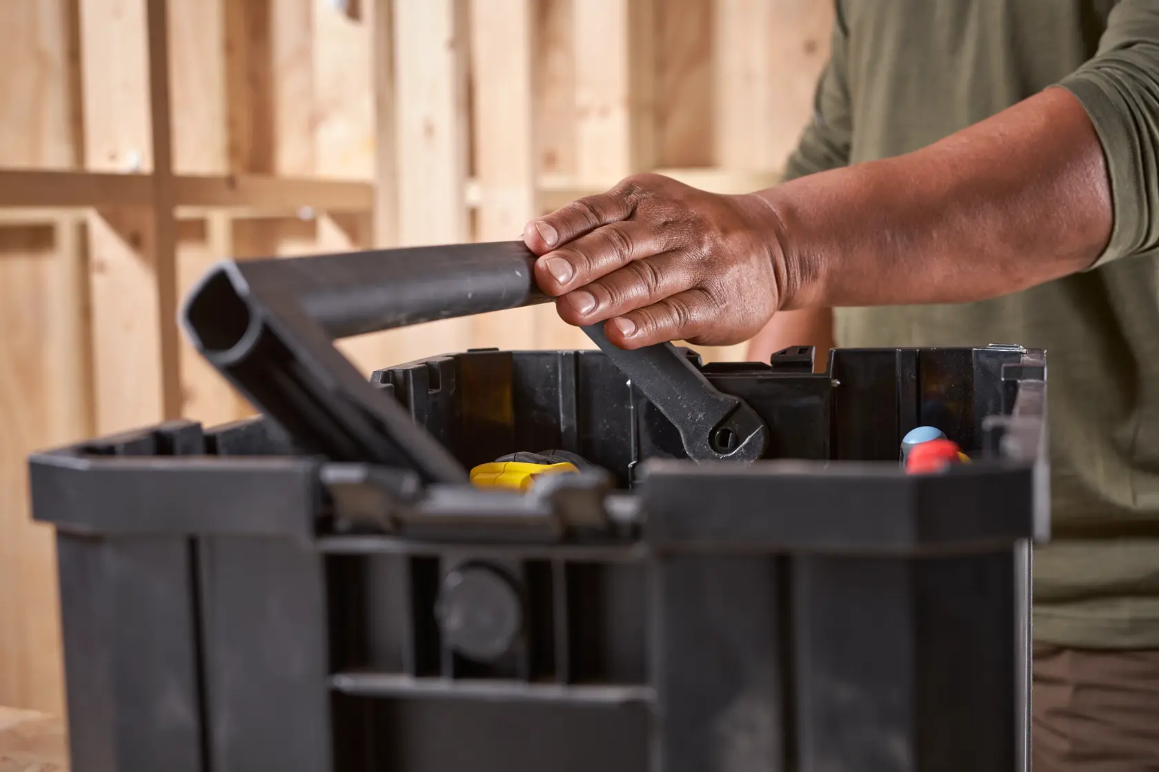 Photo of STANLEY FMST1-75794 black plastic tool box being carried by handle, tools visible inside.