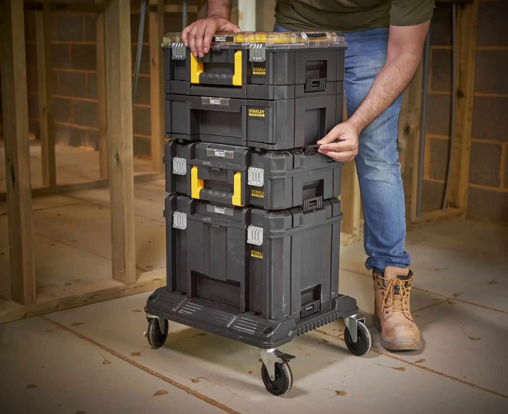 STANLEY FMST1-80107 stackable toolboxes with yellow handles on rolling cart, photographed on construction site.