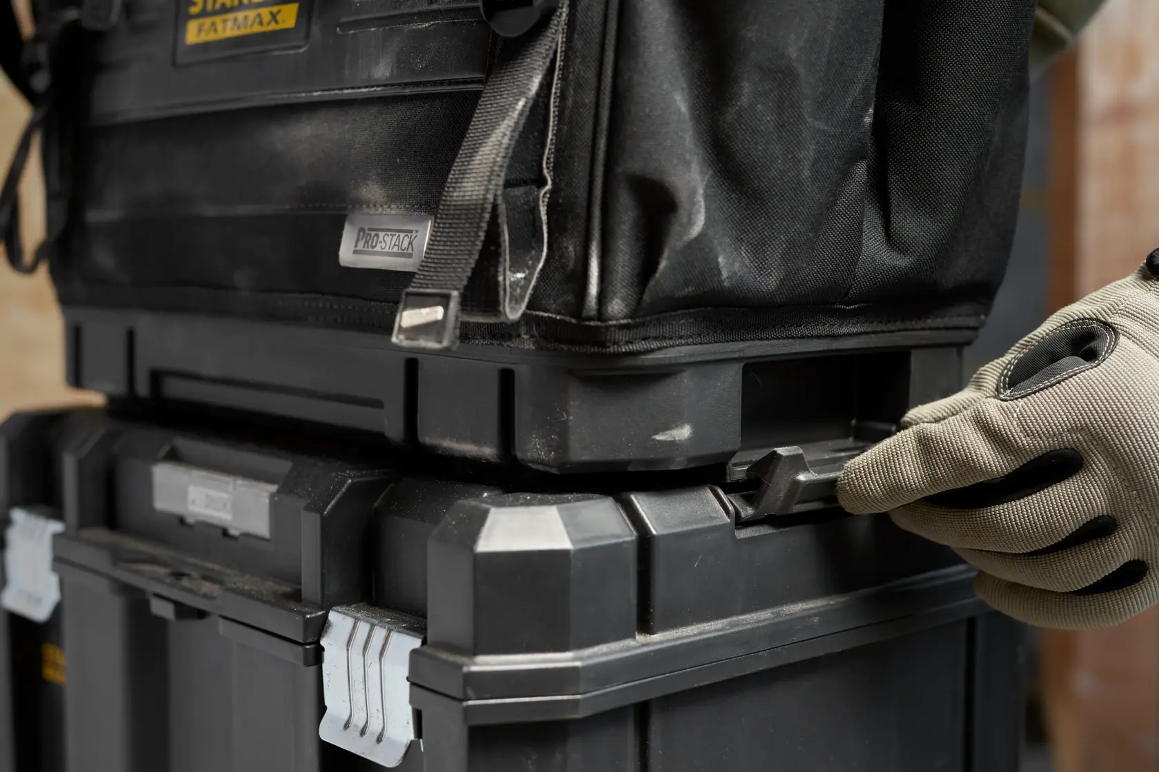 STANLEY FMST17626-1 stackable black toolboxes with side latch being handled, close-up angle.