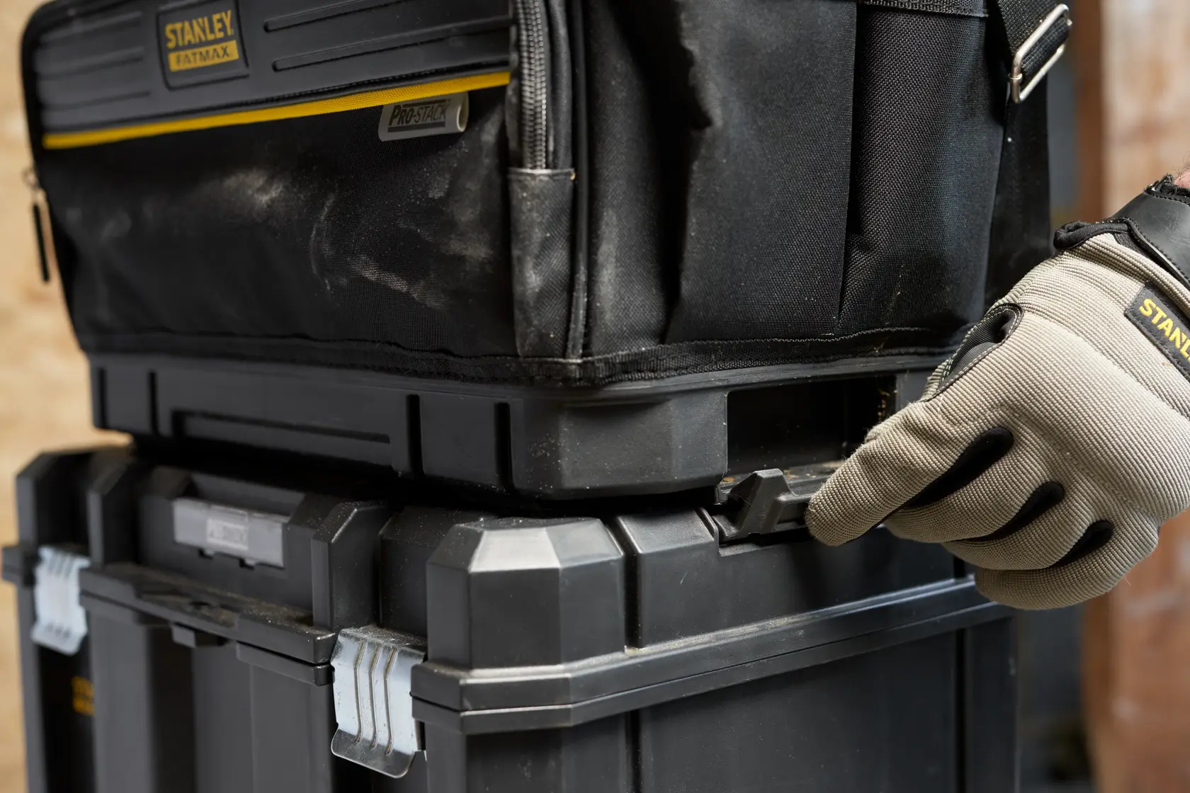 STANLEY FMST17627-1 tool box close-up, stacked modular cases, gloved hand securing latch, product side angle.