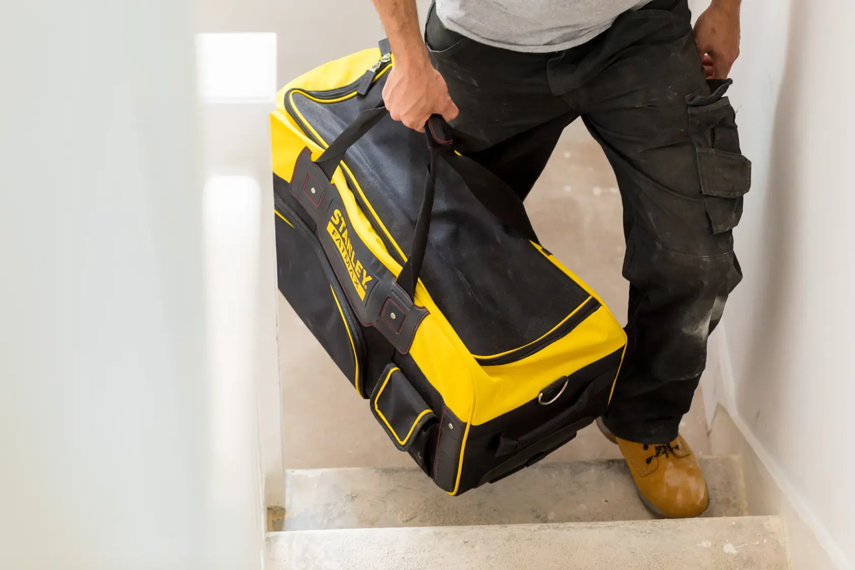 STANLEY FMST82706-1 yellow and black tool bag carried by person on staircase.