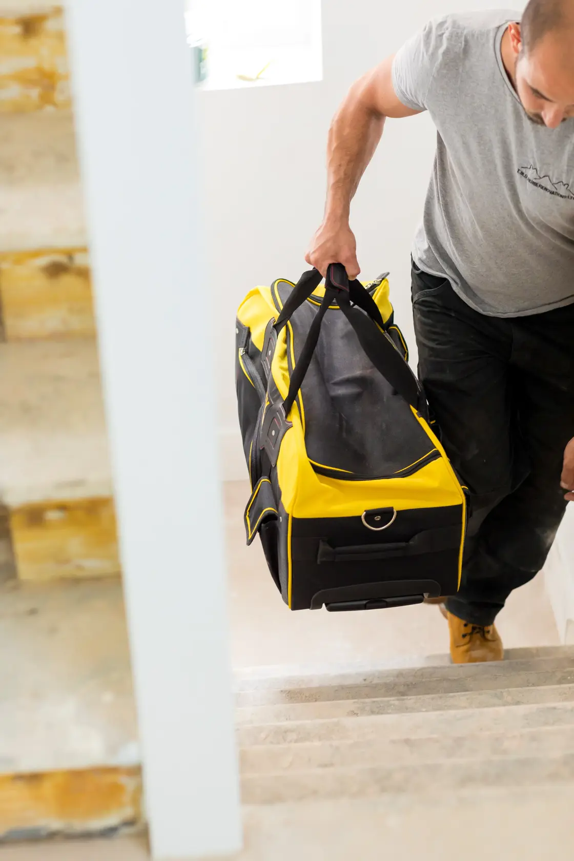 STANLEY FMST82706-1 large yellow and black tool bag carried up stairs, lifestyle context.