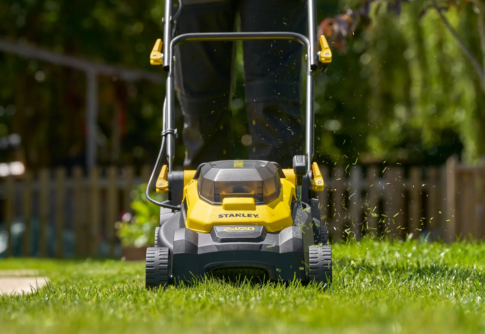Stanley SCMWP3701N lawn mower front view in use, yellow and black design on a green lawn outdoors.