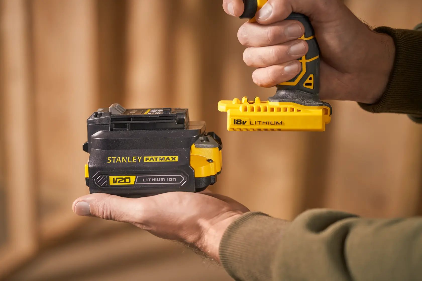 Photo of STANLEY SFMCB121D1 V20 lithium-ion battery held in hand, close-up, showing yellow and black details.
