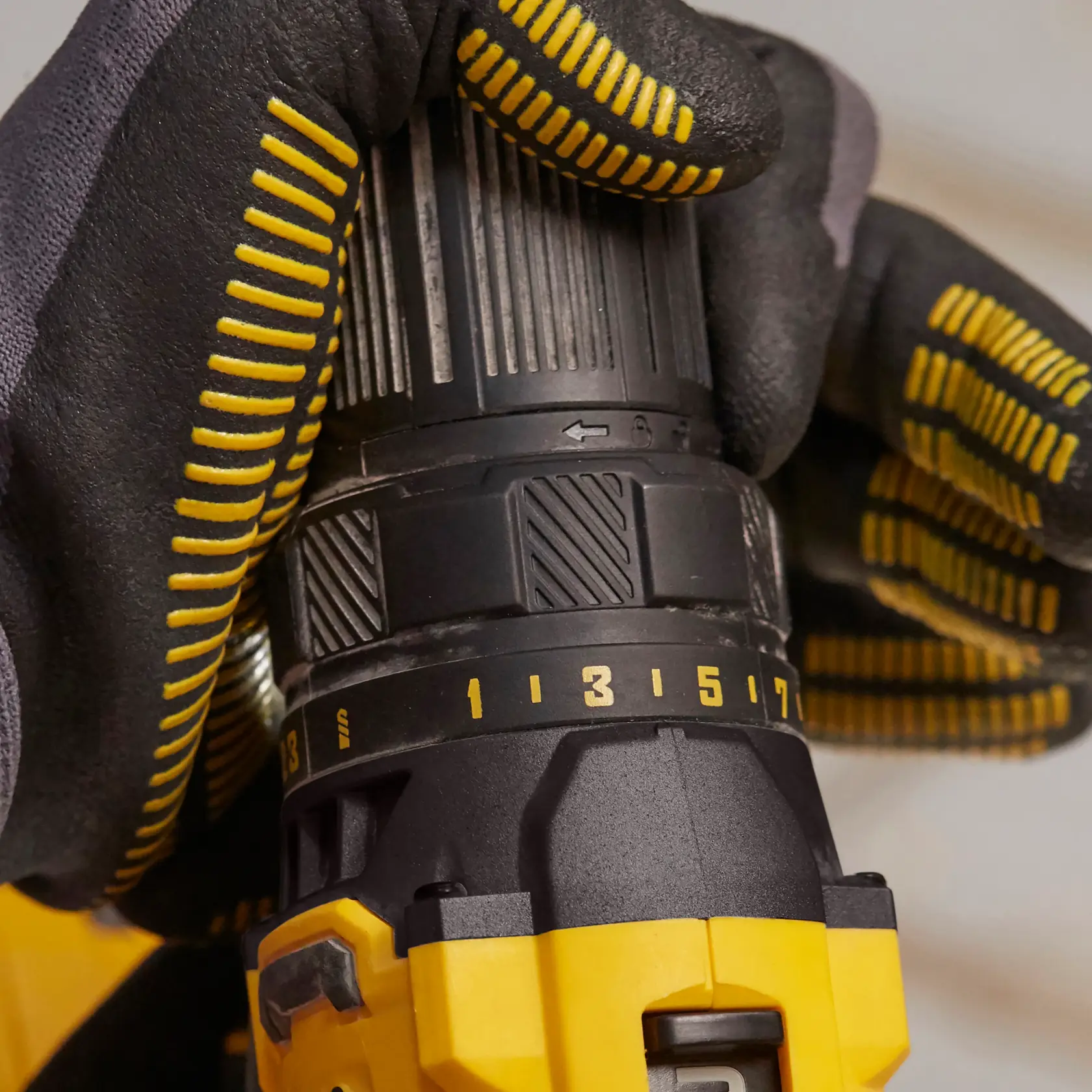 STANLEY SFMCD700C2S drill close-up, yellow and black, gloved hand adjusting torque settings.