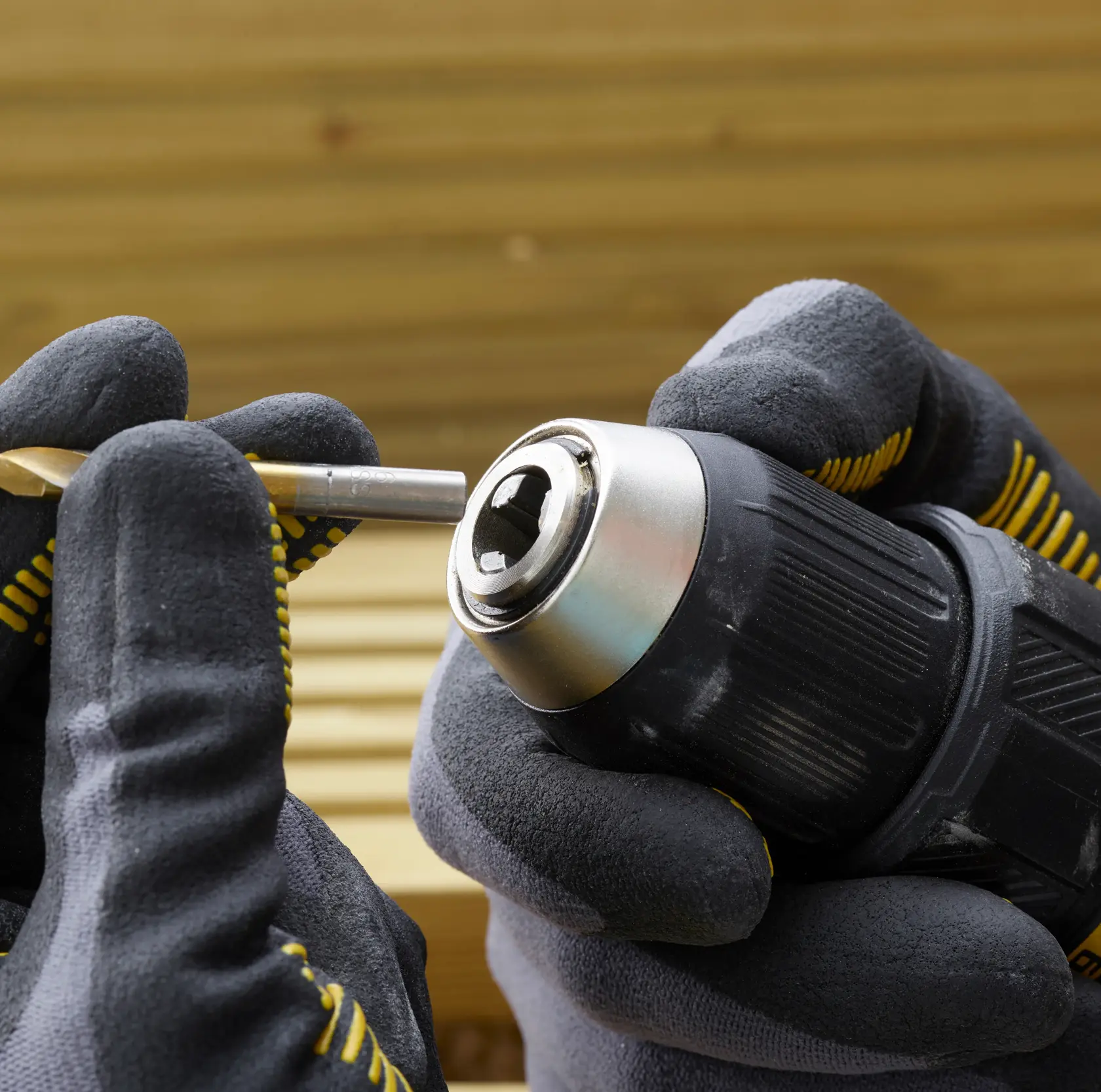 STANLEY SFMCD710D2K drill held in gloved hands, inserting a drill bit, close-up view.