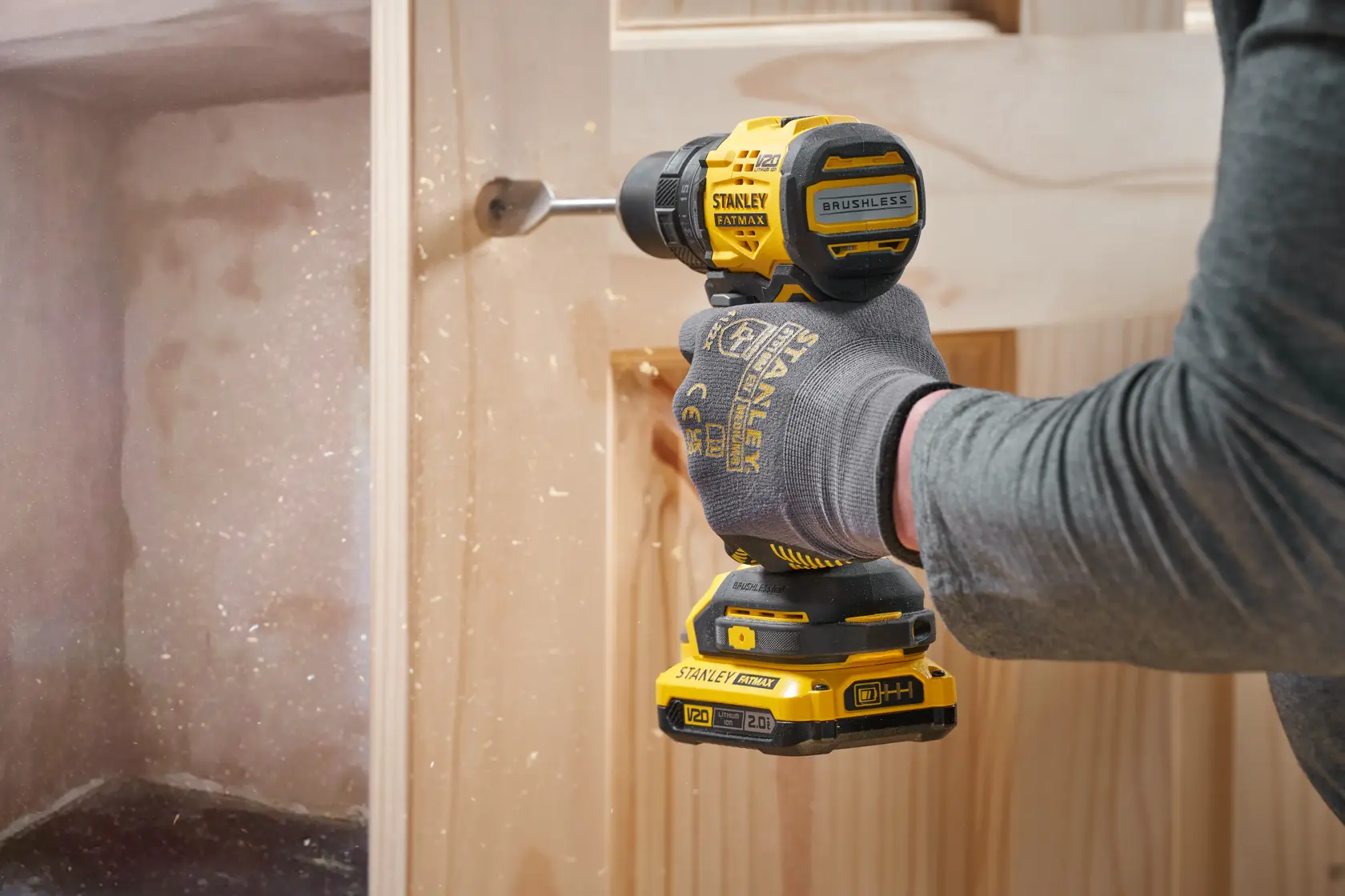 STANLEY SFMCD714B-XJ cordless drill in use, drilling into wood, side view, yellow and black power tool.