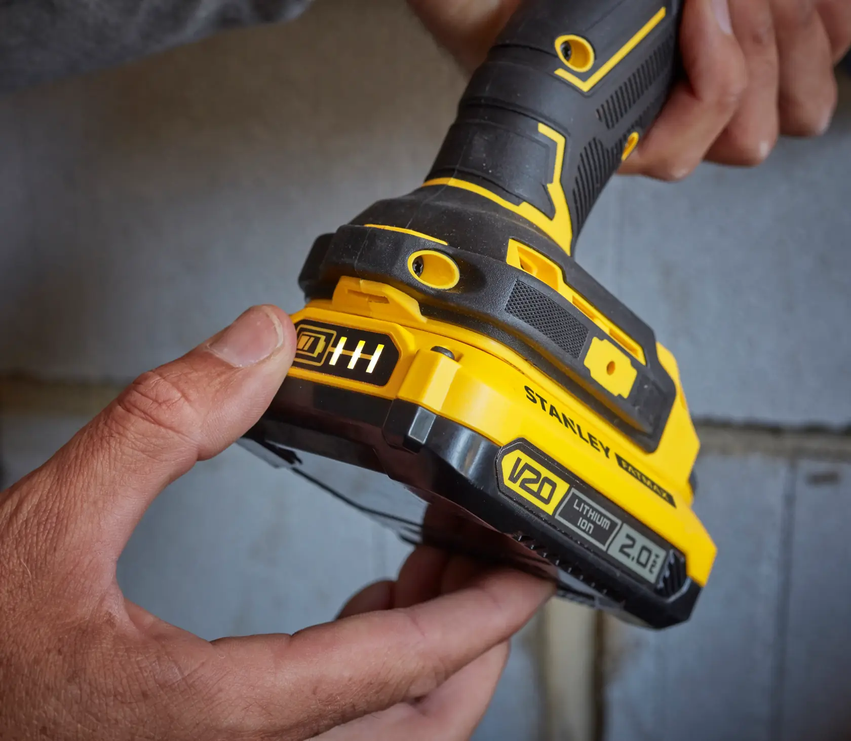 Photo of STANLEY SFMCD715D2K cordless drill, close-up of yellow and black handle and V20 battery.