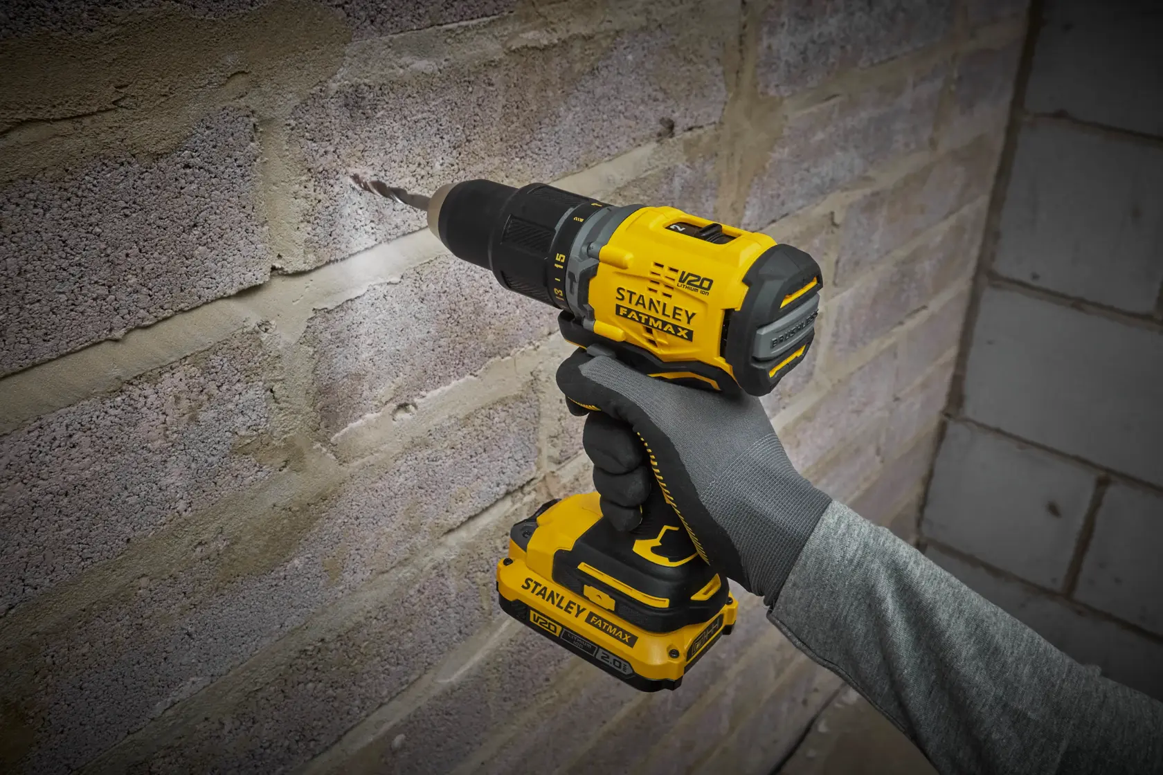 STANLEY SFMCD715D2K cordless drill in use drilling into a brick wall, shown in a close-up side angle.