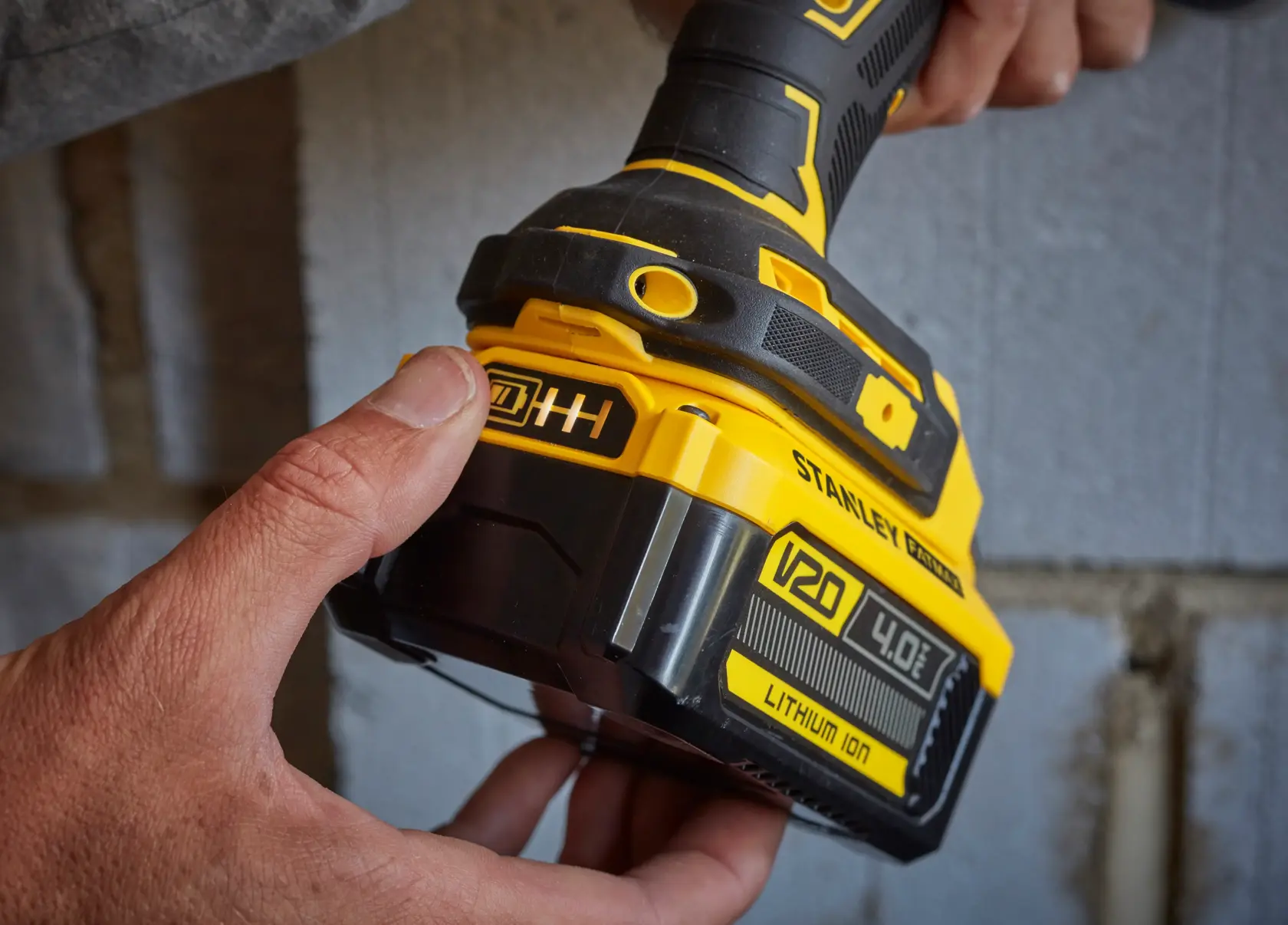 Photo of STANLEY SFMCD715M2K cordless drill with V20 4.0Ah lithium-ion battery being held near a wall.